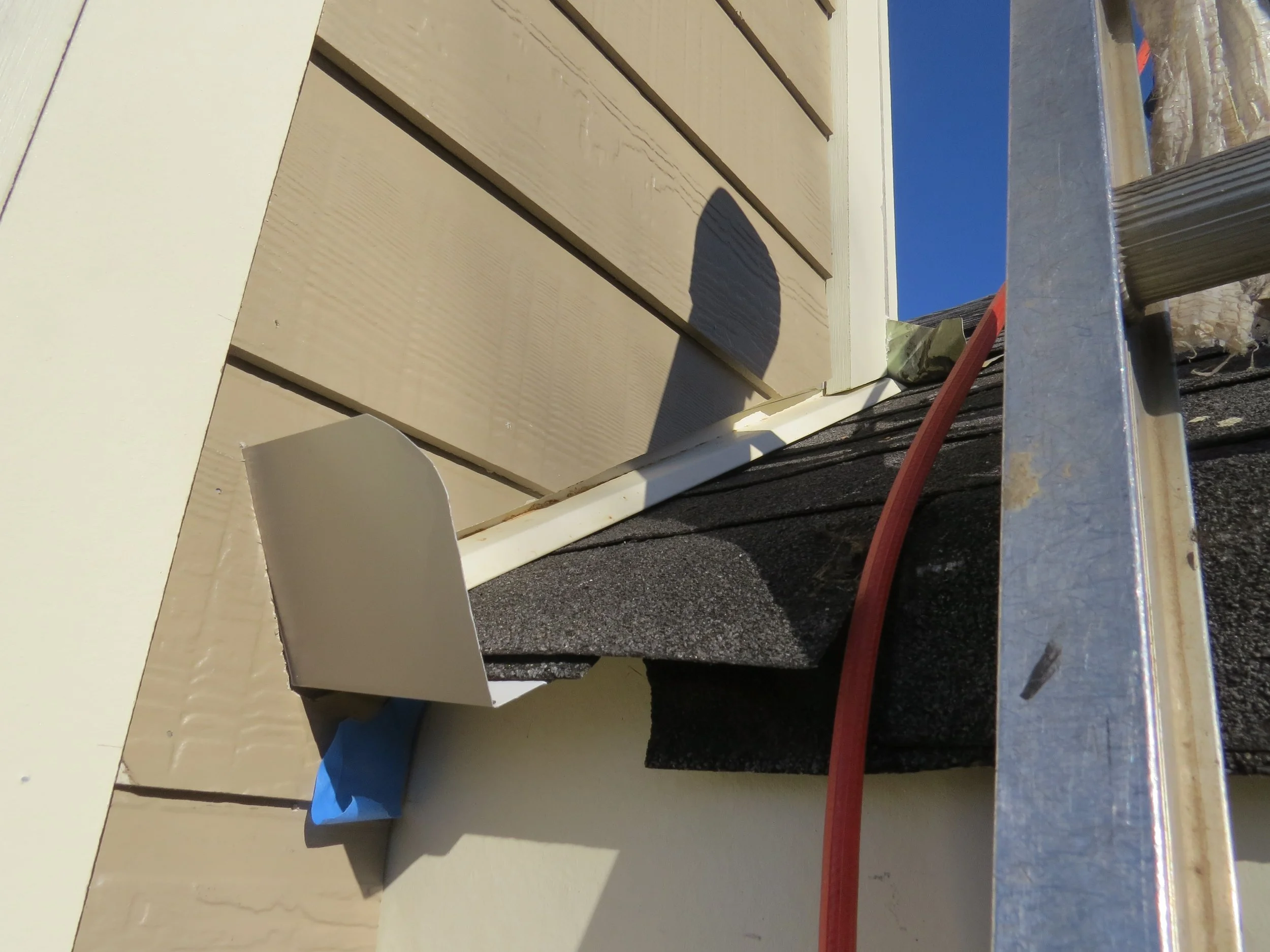 Roof-to-wall siding intersection with kickout flashing installed to direct roof runoff into the gutter and protect against water intrusion.