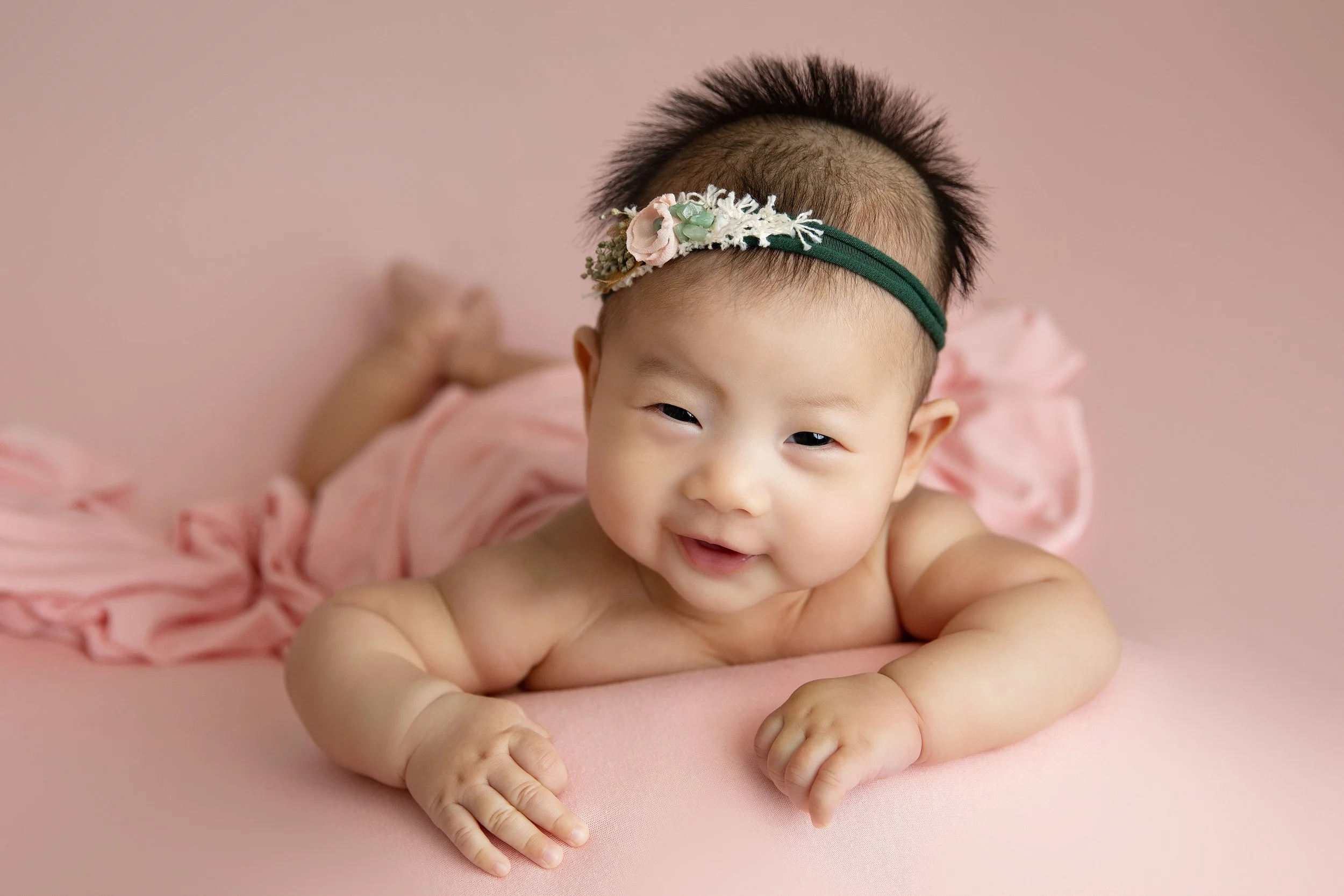 100 day old newborn girl with pink backdrop and smiling