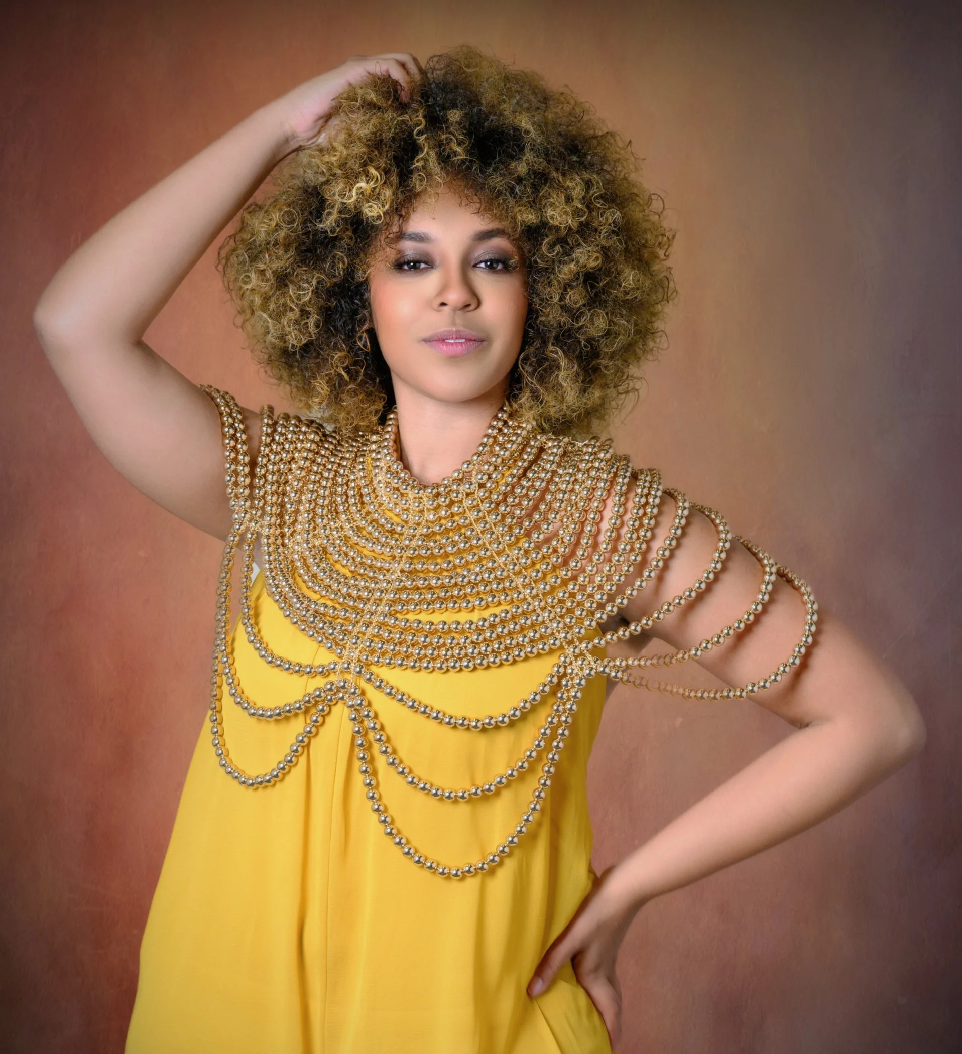 Professional portrait of a woman wearing a yellow dress with gold beaded detailing.