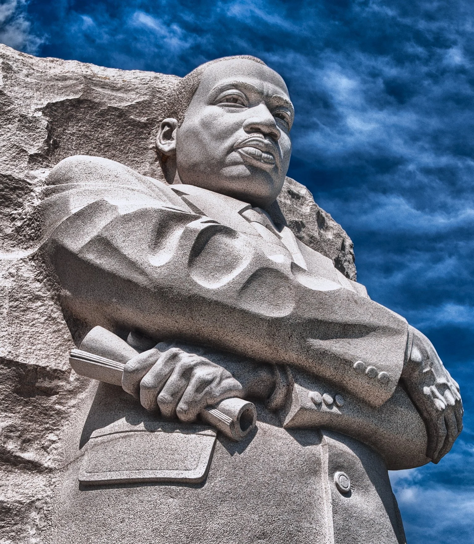Close-up of the Mount Rushmore National Memorial featuring the carved faces of four U.S. Presidents against a blue sky with clouds.