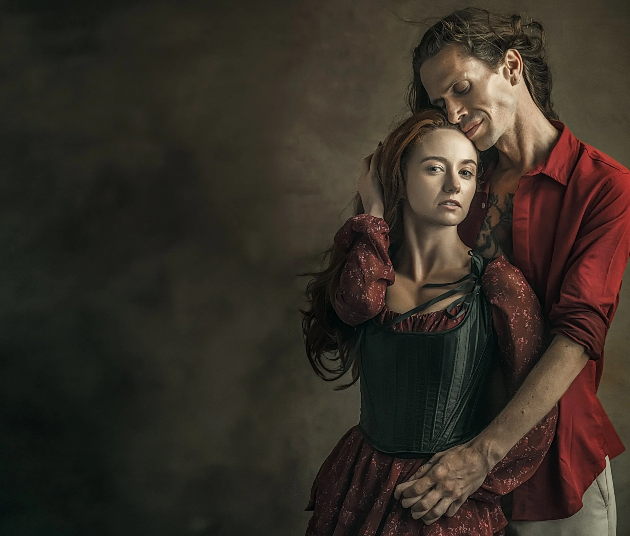 Creative portrait of a couple wearing richly textured red, and black clothing.