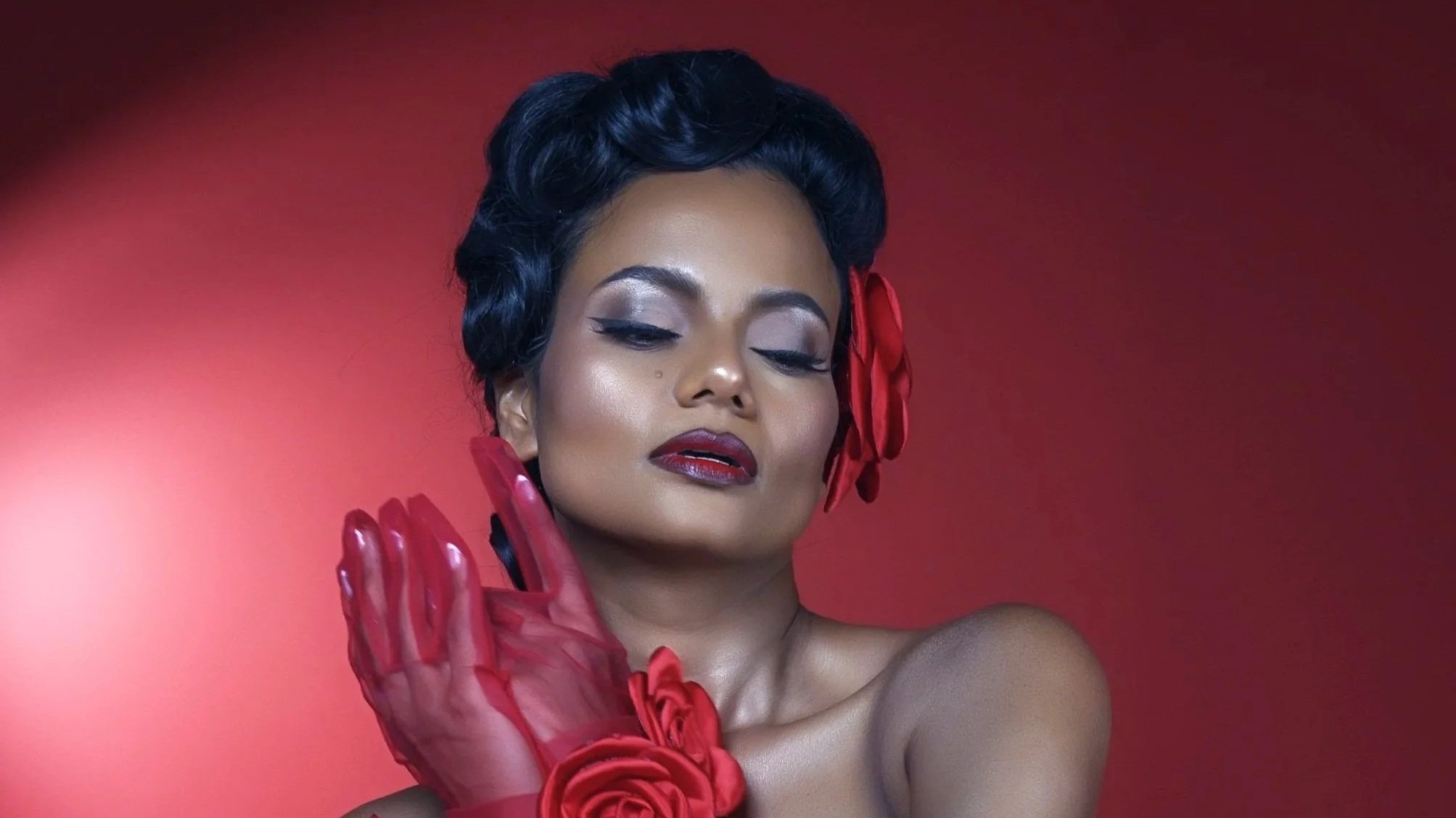 Fine art portrait of a woman wearing red styling with dramatic studio lighting.