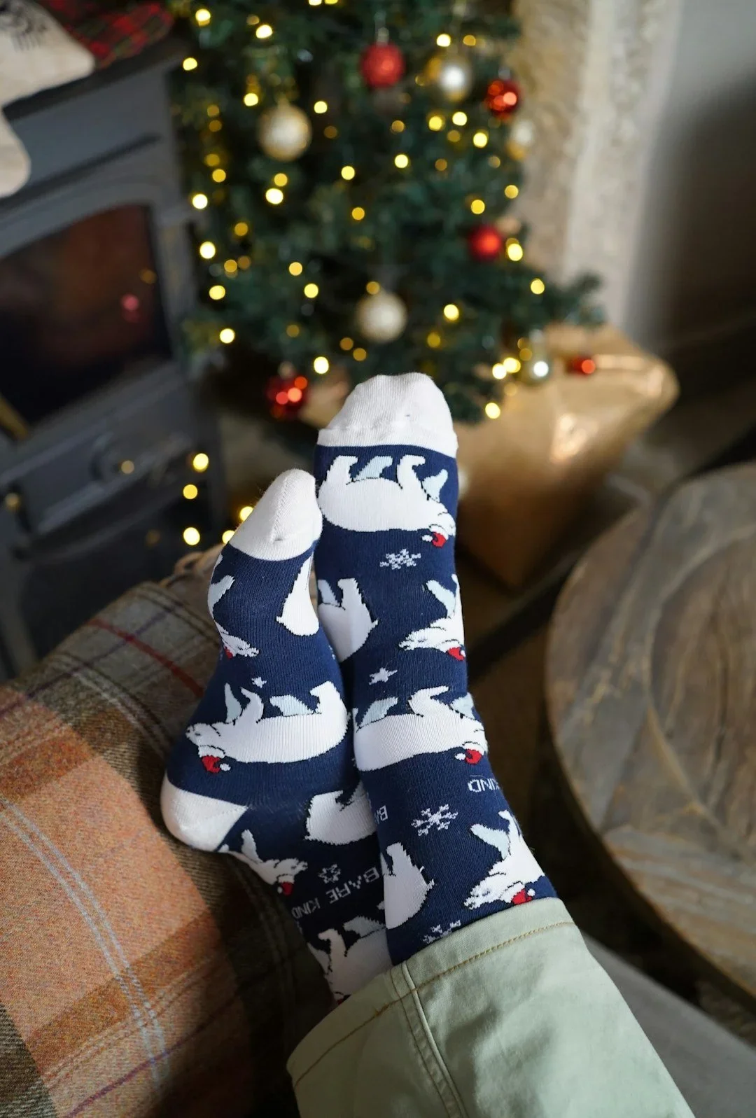 feet crossed on couch wearing polar bear socks in front of a Christmas tree