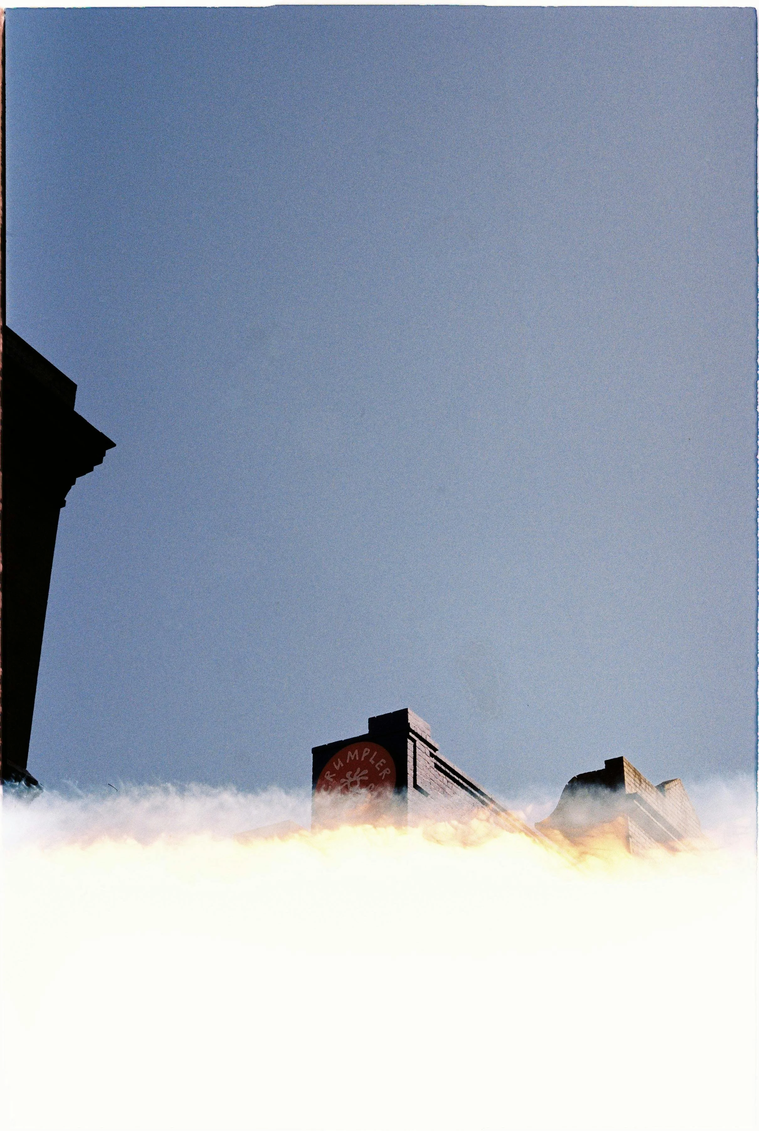 A clear blue sky above rooftops of buildings with signage. The image appears to be upside down.