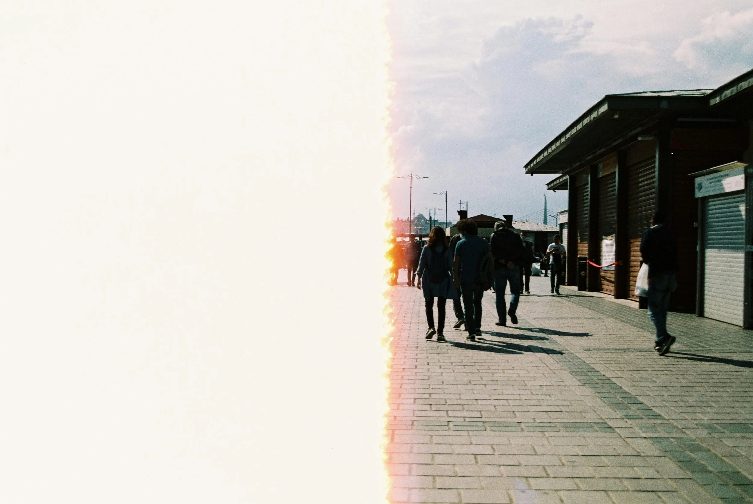 People walking outside near a building with roller shutter doors during daytime.