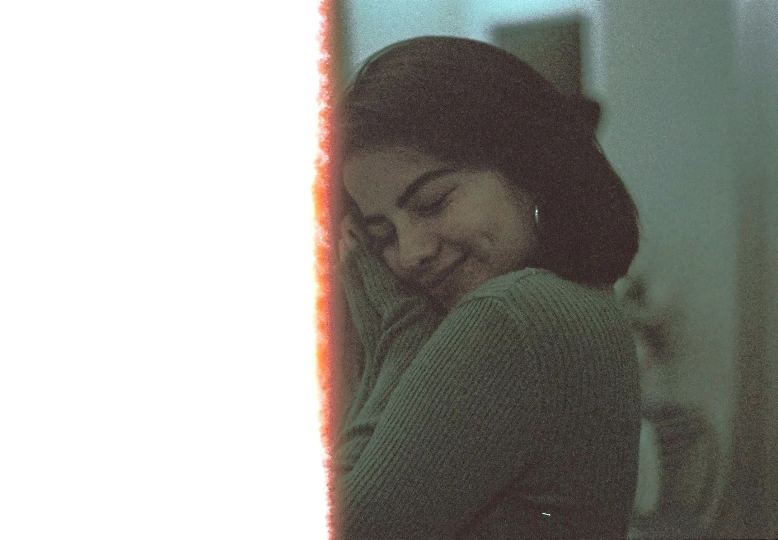 A woman with dark hair smiling and hugging a person wearing glasses and a striped shirt, with a sunset or sunrise sky in the background.