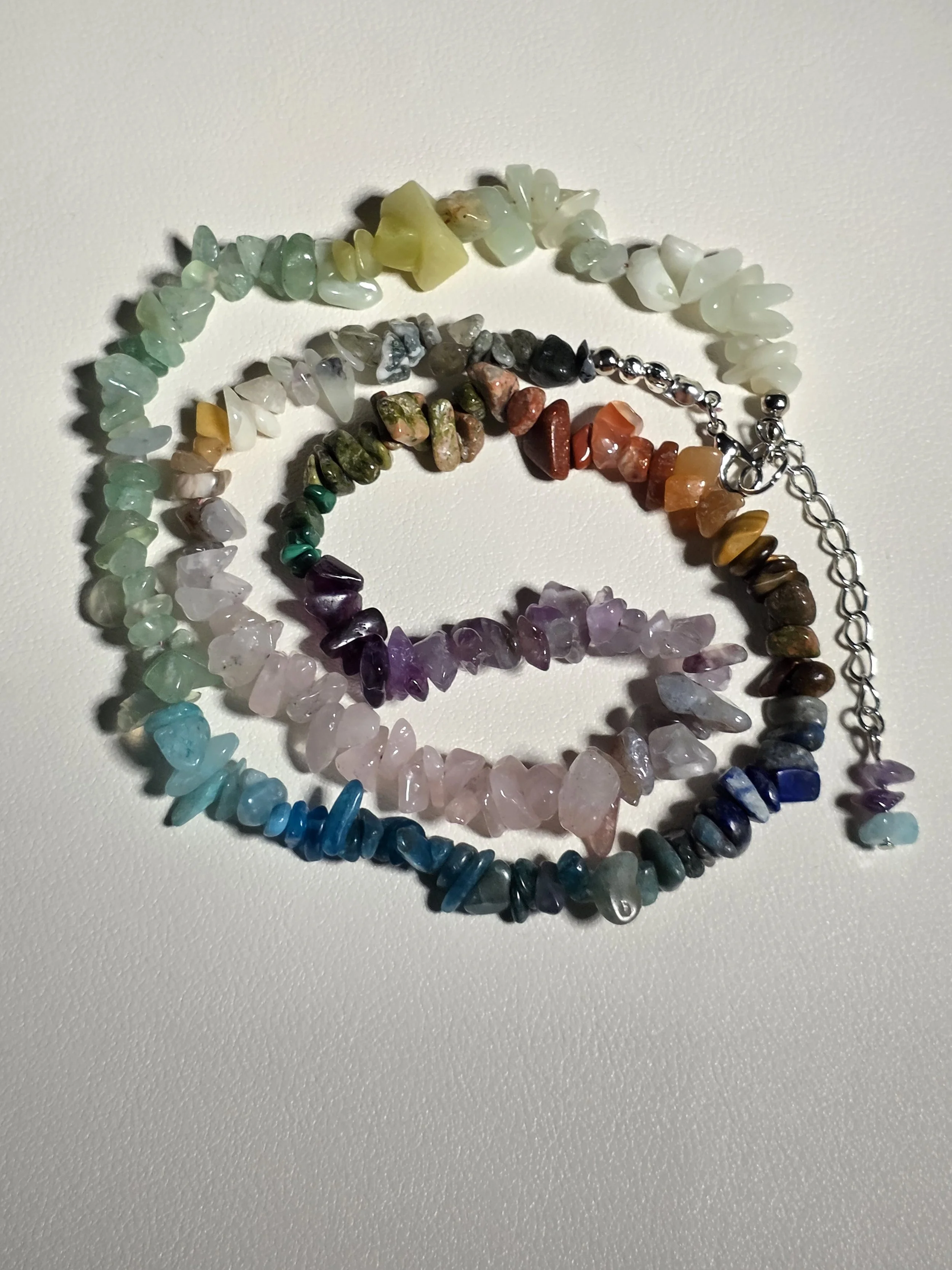 Colorful gemstone beaded necklaces with a chain clasp, arranged on a white surface.