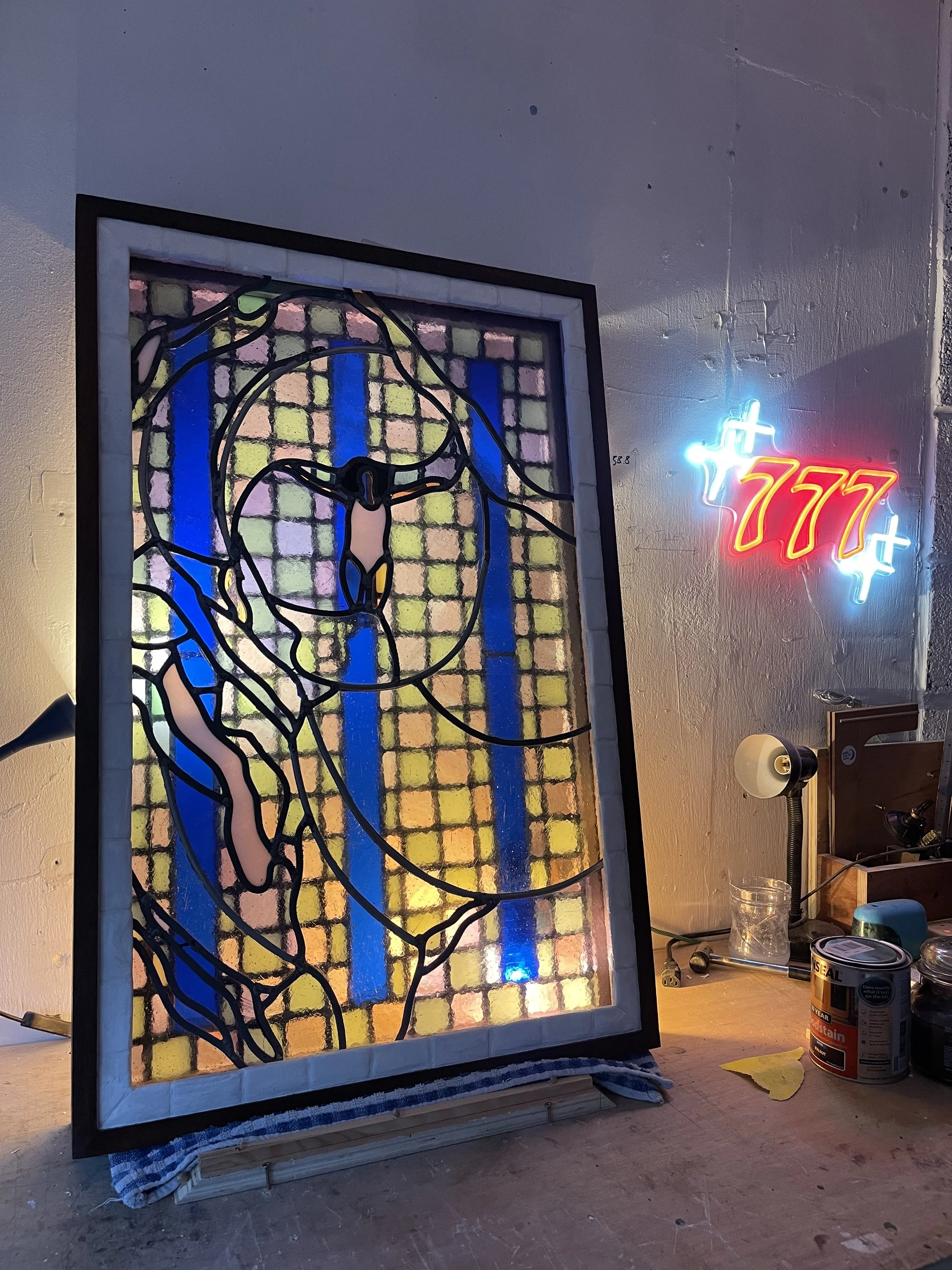 A stained glass artwork in progress featuring a portrait of a woman, floating in a swimming pool.
