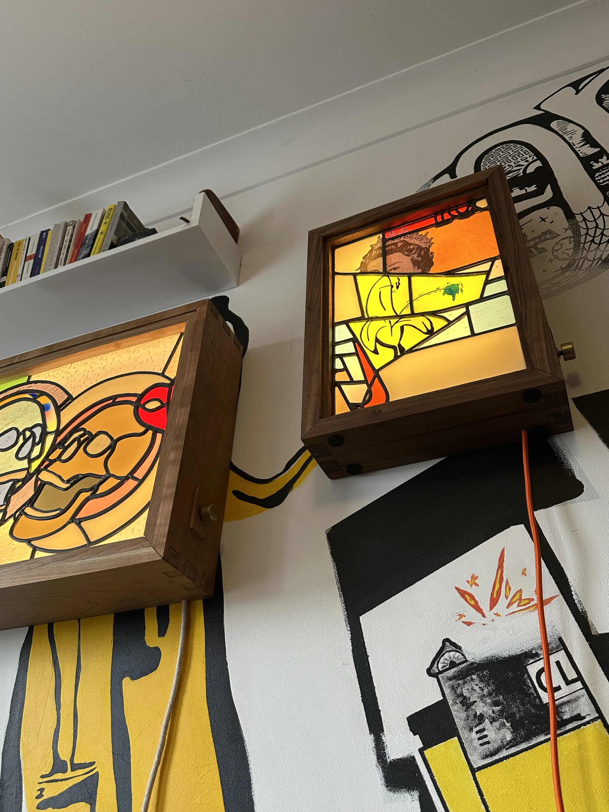 Close-up of two, contemporary stained glass light fixtures with wooden frames.