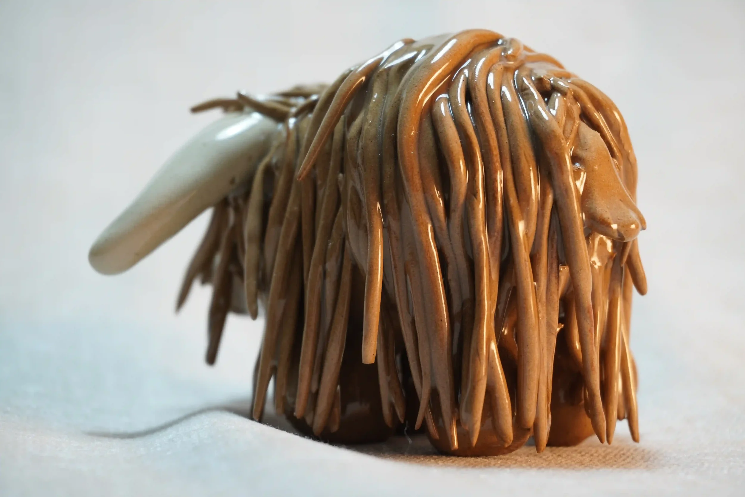 Rear view of a cute, handmade, ceramic, milk chocolate-coloured Highland Cow ornament