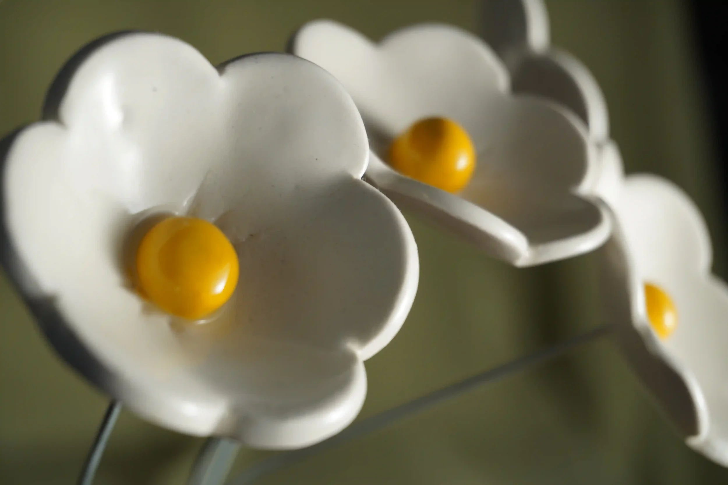Close-up of several handcrafted white ceramic daisy flowers