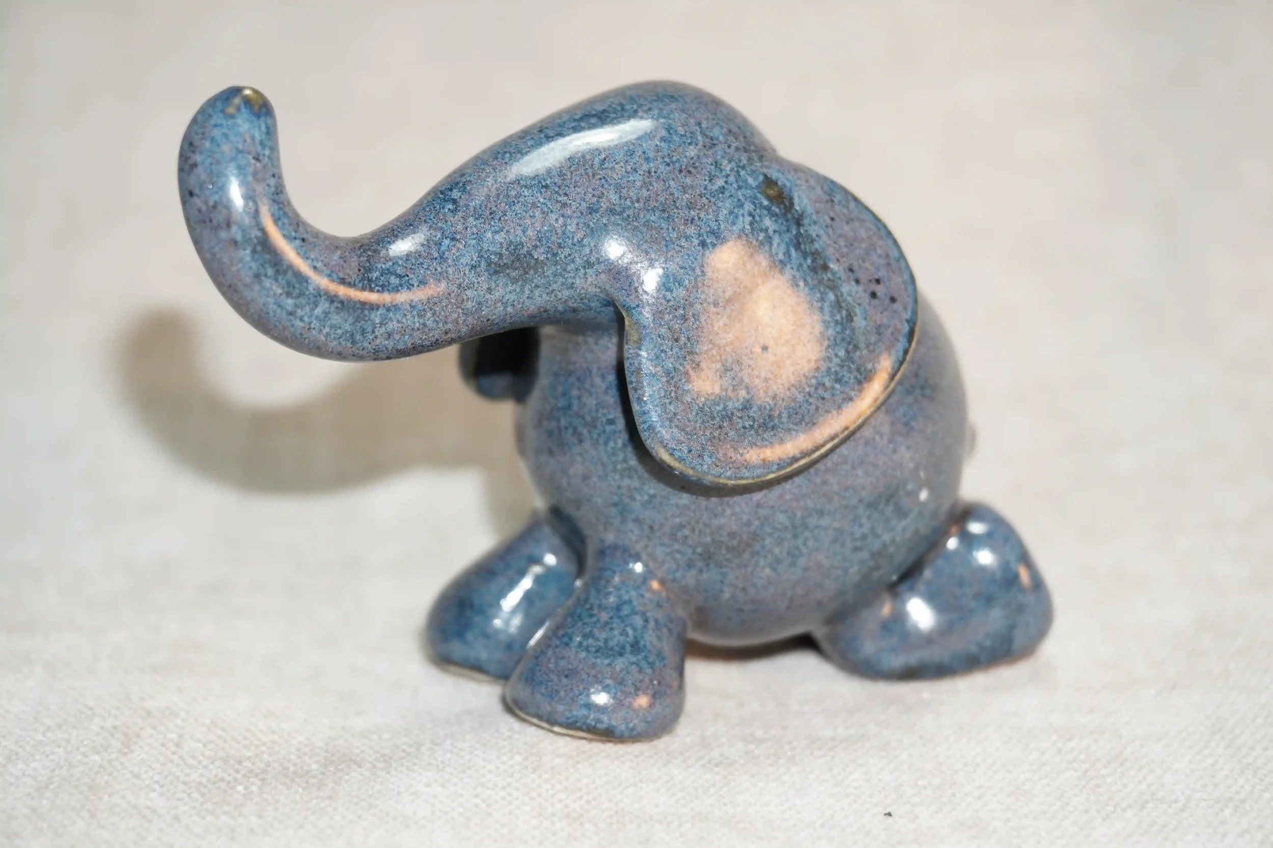 A small ceramic elephant figurine with a blue-gray speckled glaze on a light surface.