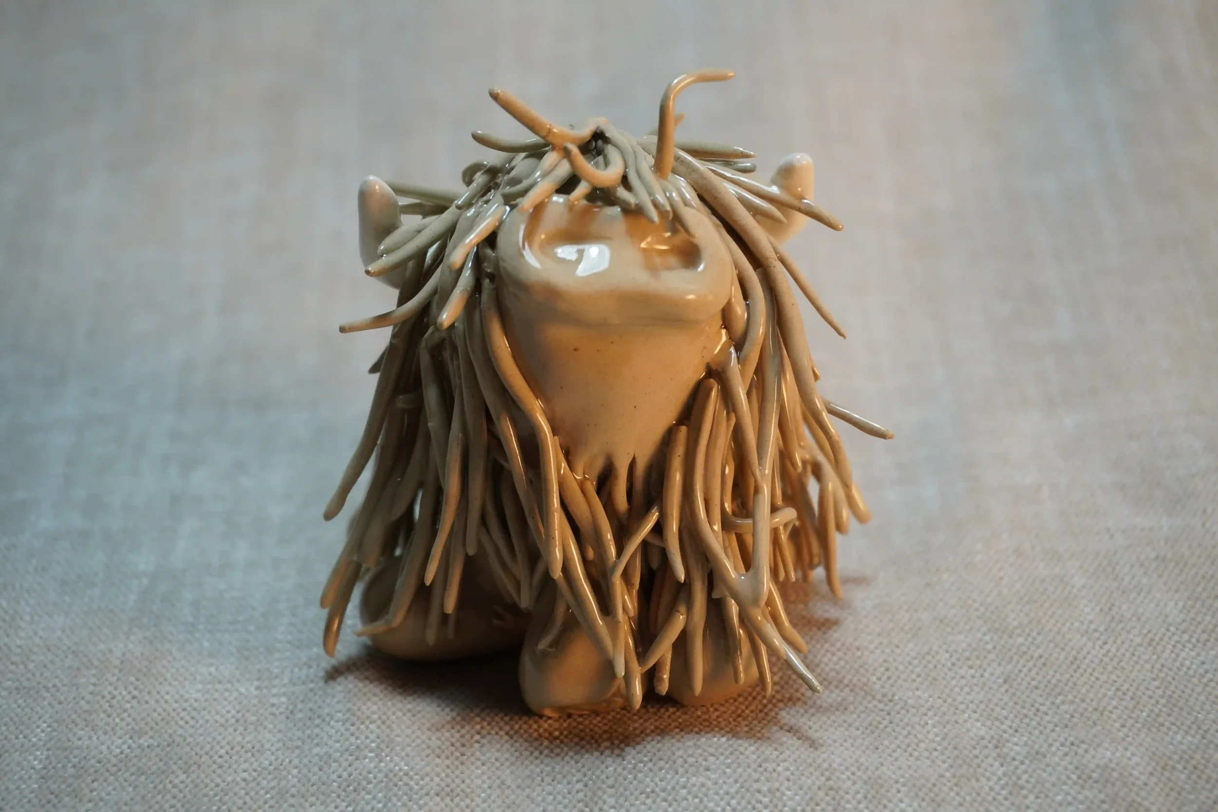 Front view of a cute, handmade ceramic Highland Cow ornament in a milk chocolate-colour with beige horns.