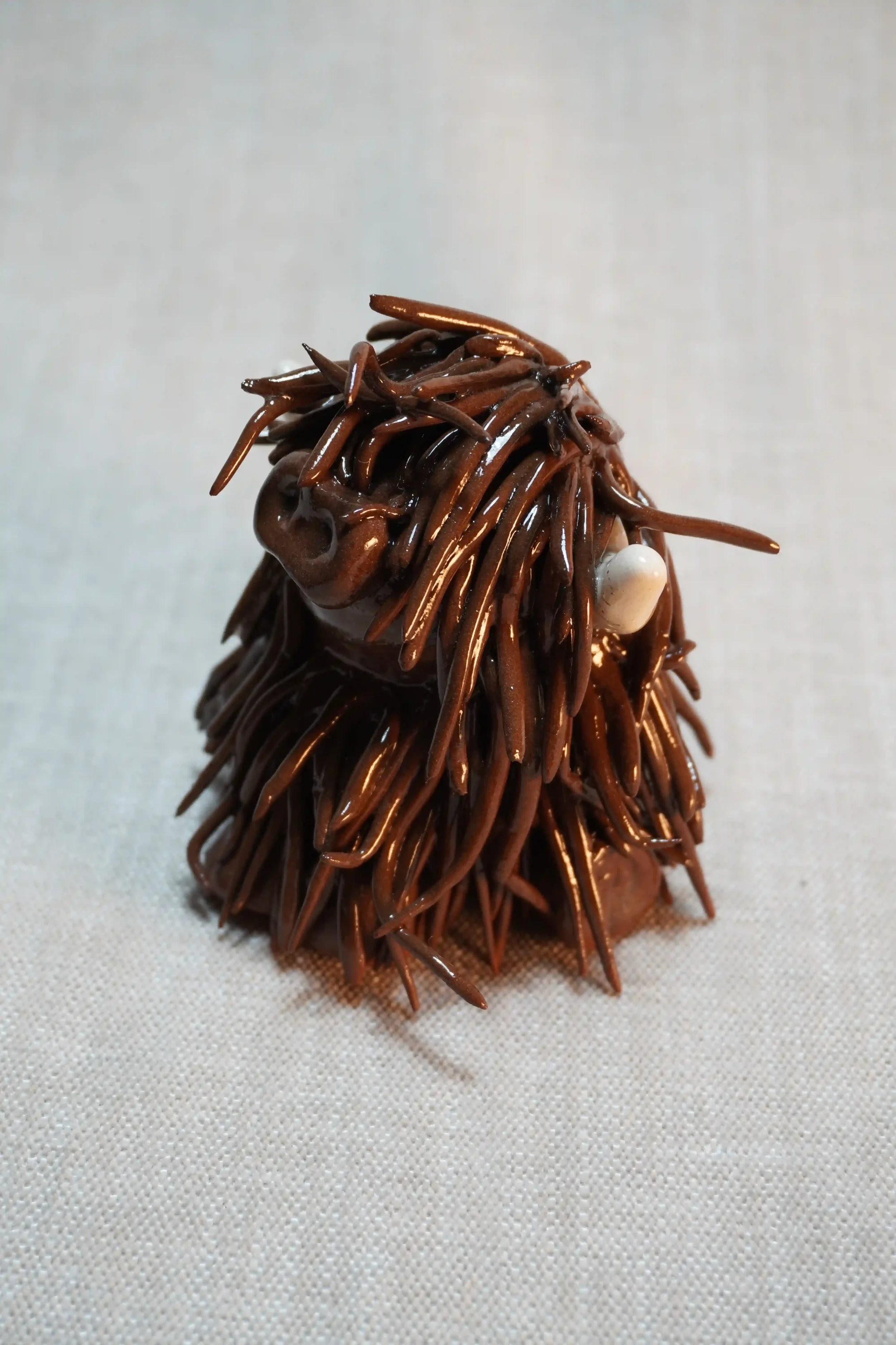 	
Side view of a ceramic sculpture of a Highland Cow ornament with rich dark brown-coloured hair and beige horns.