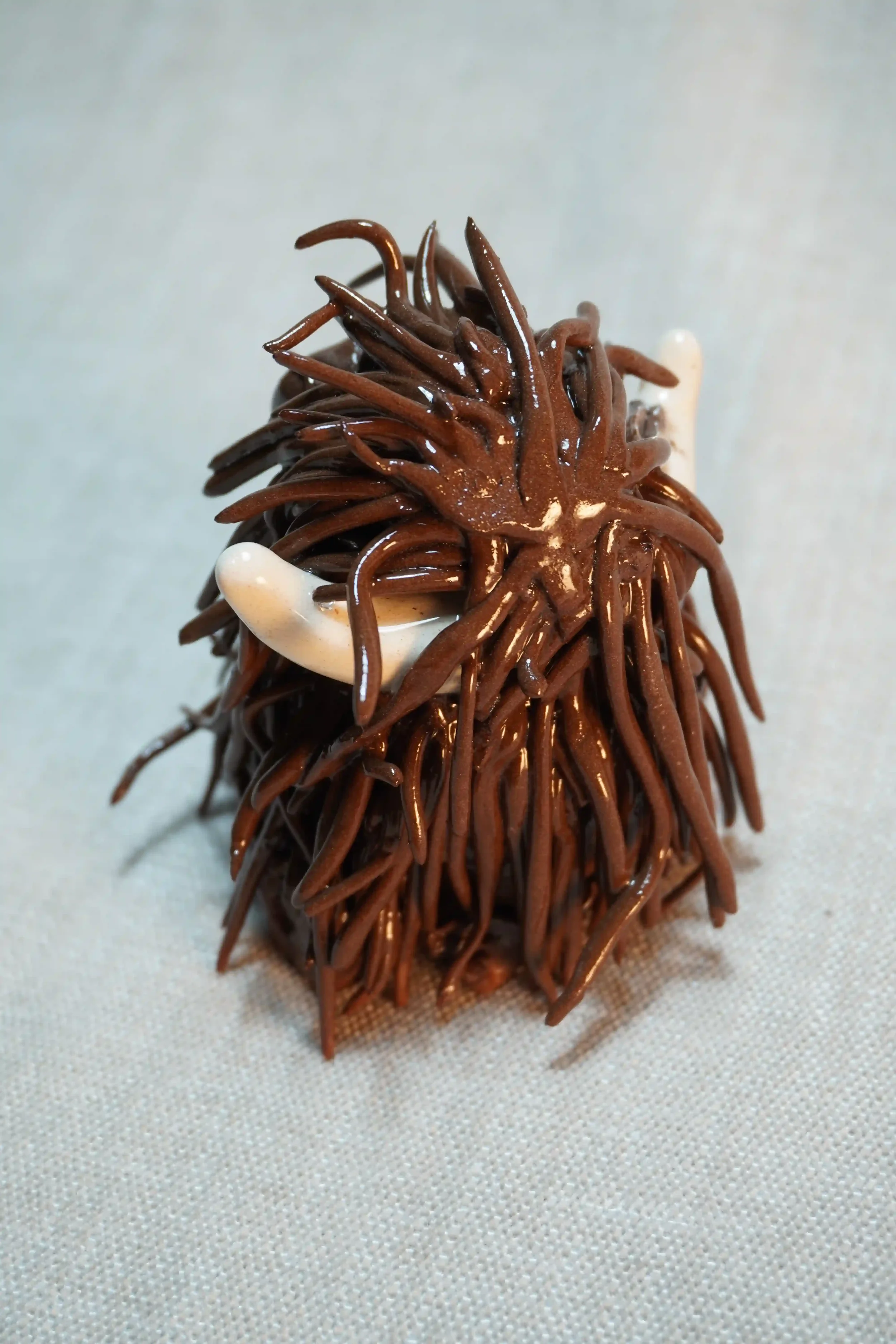 	
Rear view of a ceramic sculpture of a Highland Cow ornament with rich dark brown-coloured hair and beige horns.