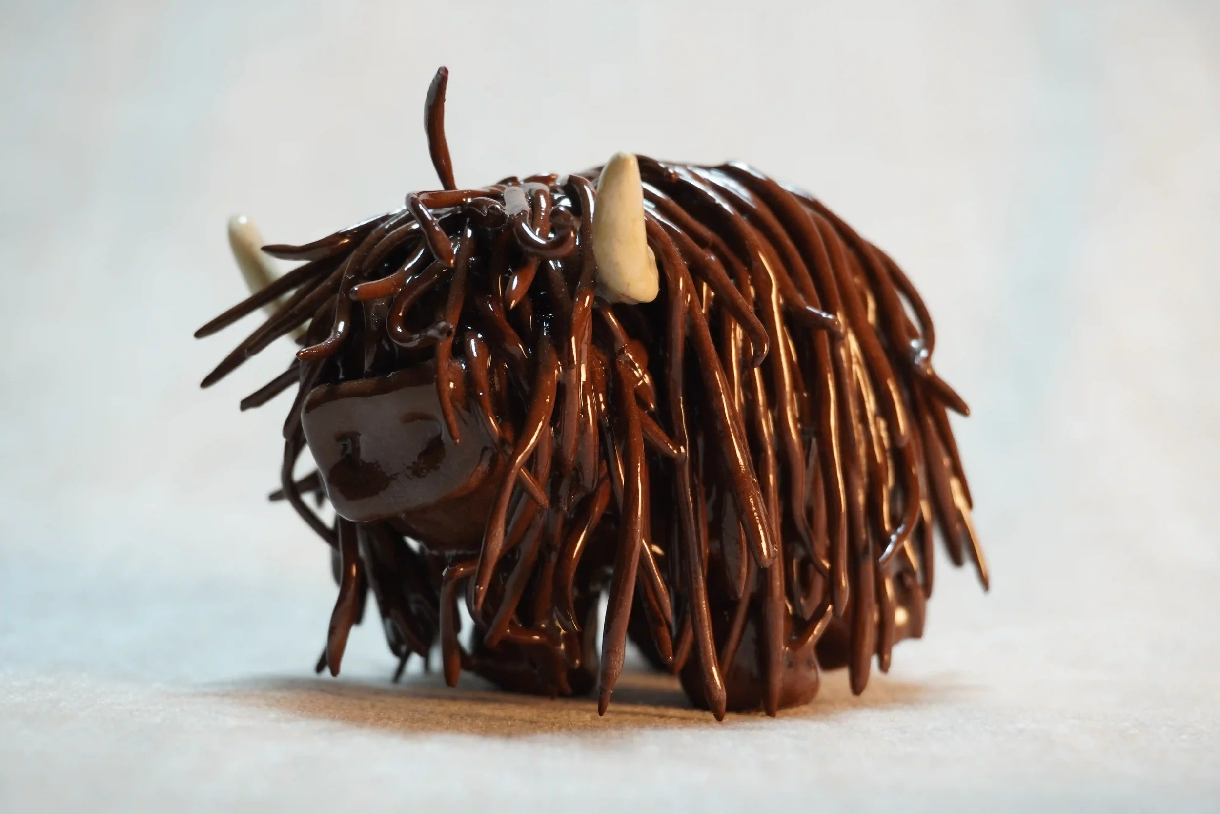 	
Side view of a ceramic sculpture of a Highland Cow ornament with dark brown-coloured hair and beige horns.