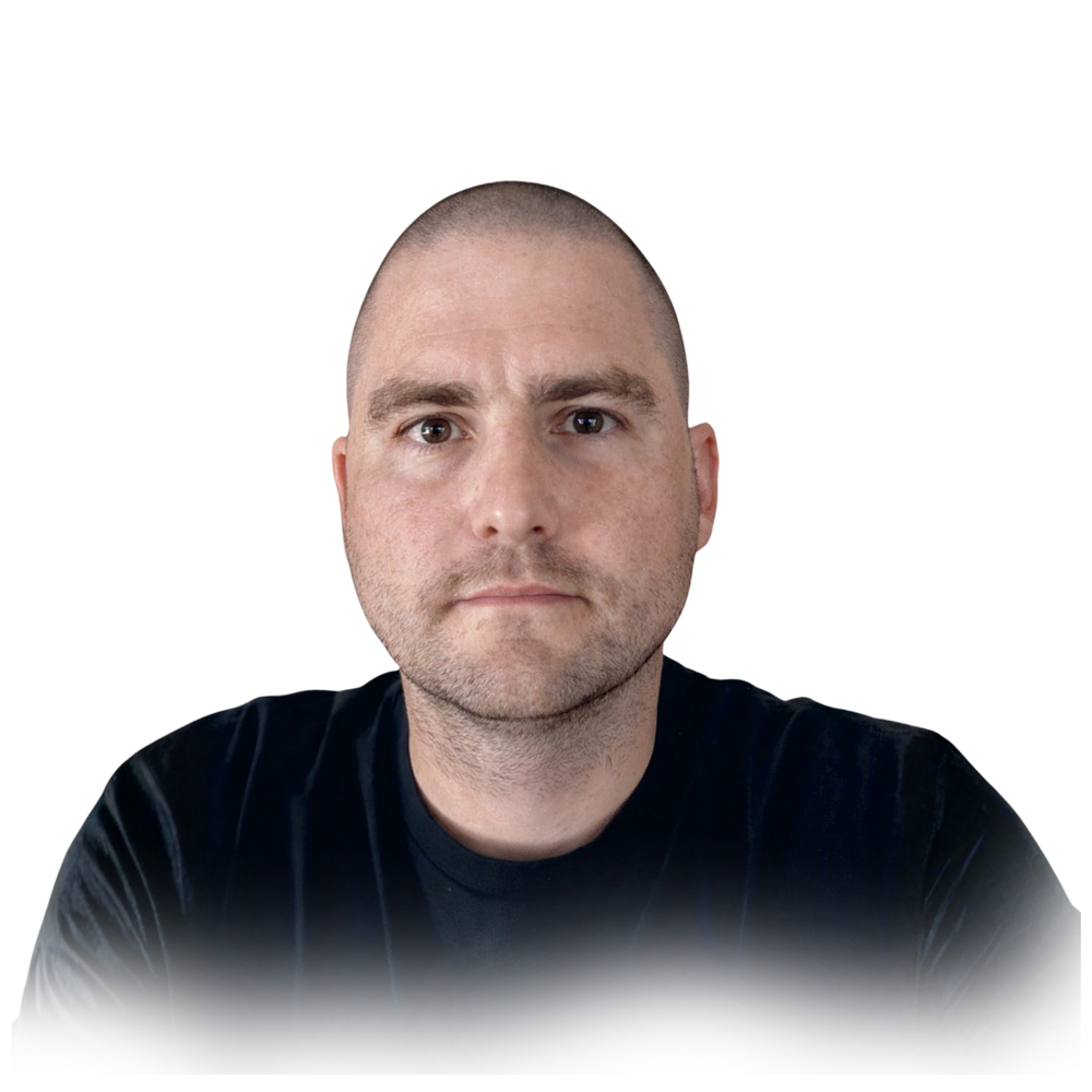 Myeloma patient Joe, with a shaved head and light facial hair, wearing a black shirt, sits against a white background.