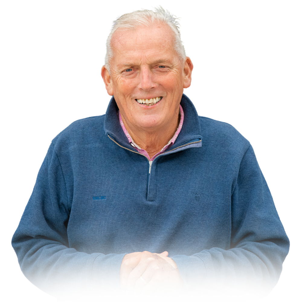 Sandy Roberts smiling, wearing a blue pullover with a zipper, with his hands clasped together