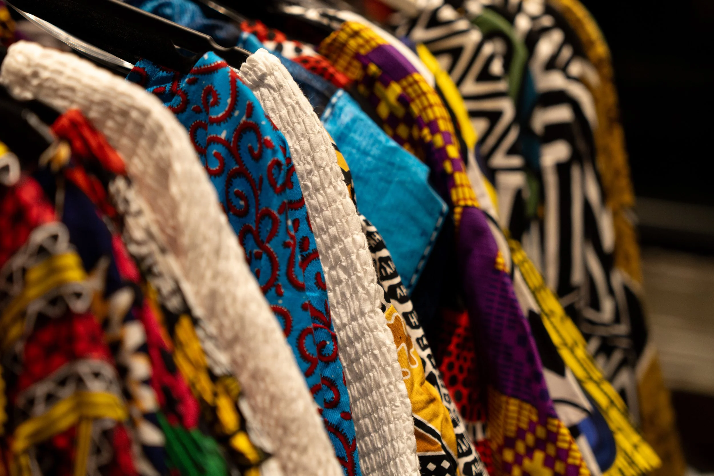 Colorful handmade fabric face masks hanging on a rack.
