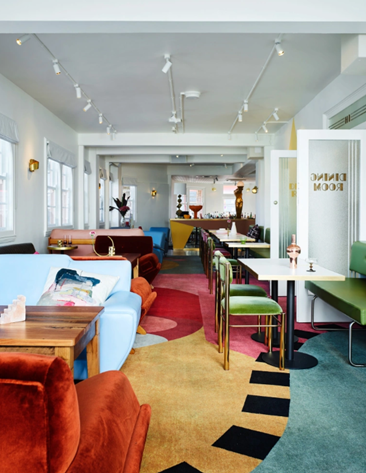 Colorful interior of a modern cafe or lounge with sofas, chairs, tables, and decorative cushions.