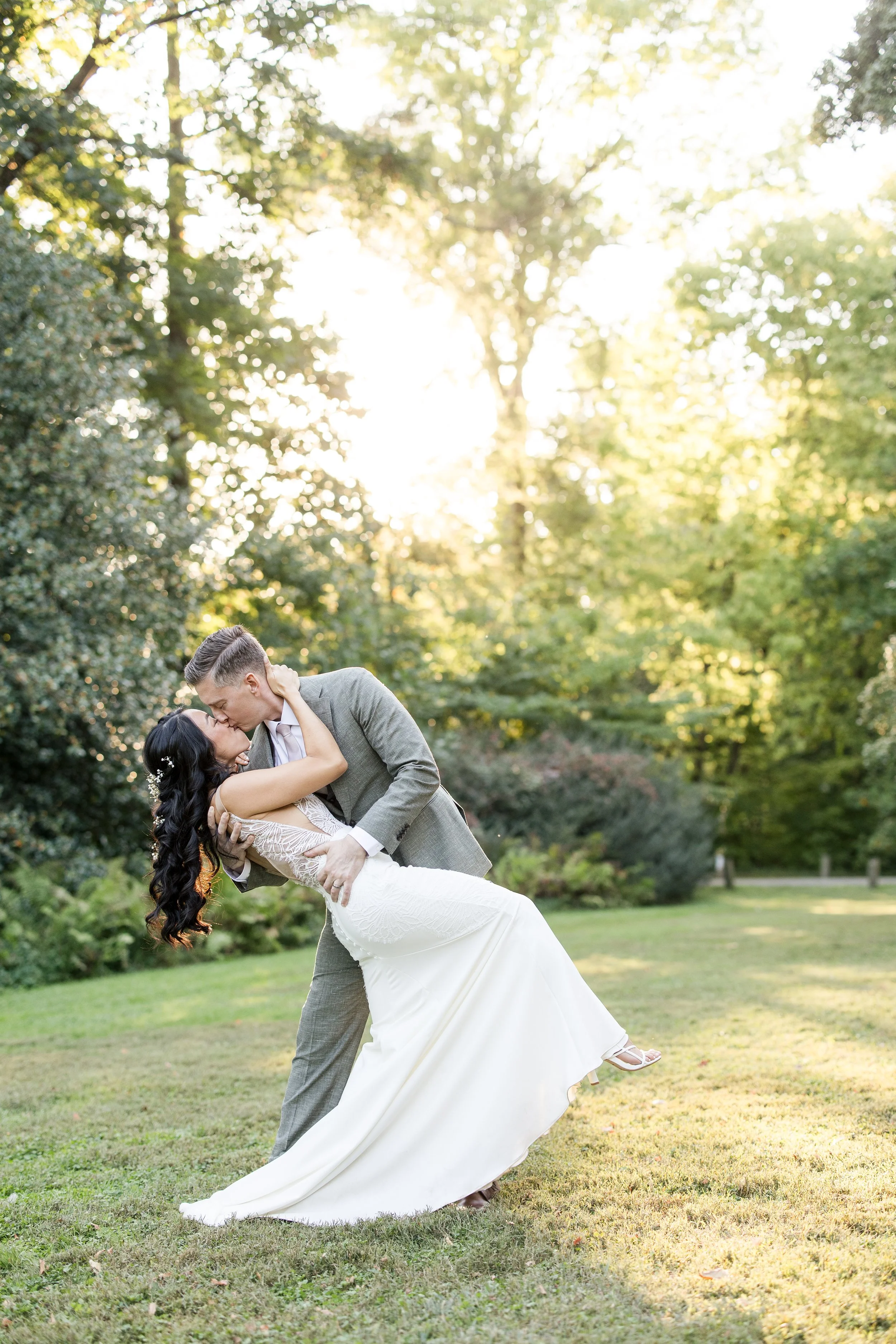 Groom dipping his bride during romantic outdoor wedding portraits at sunset