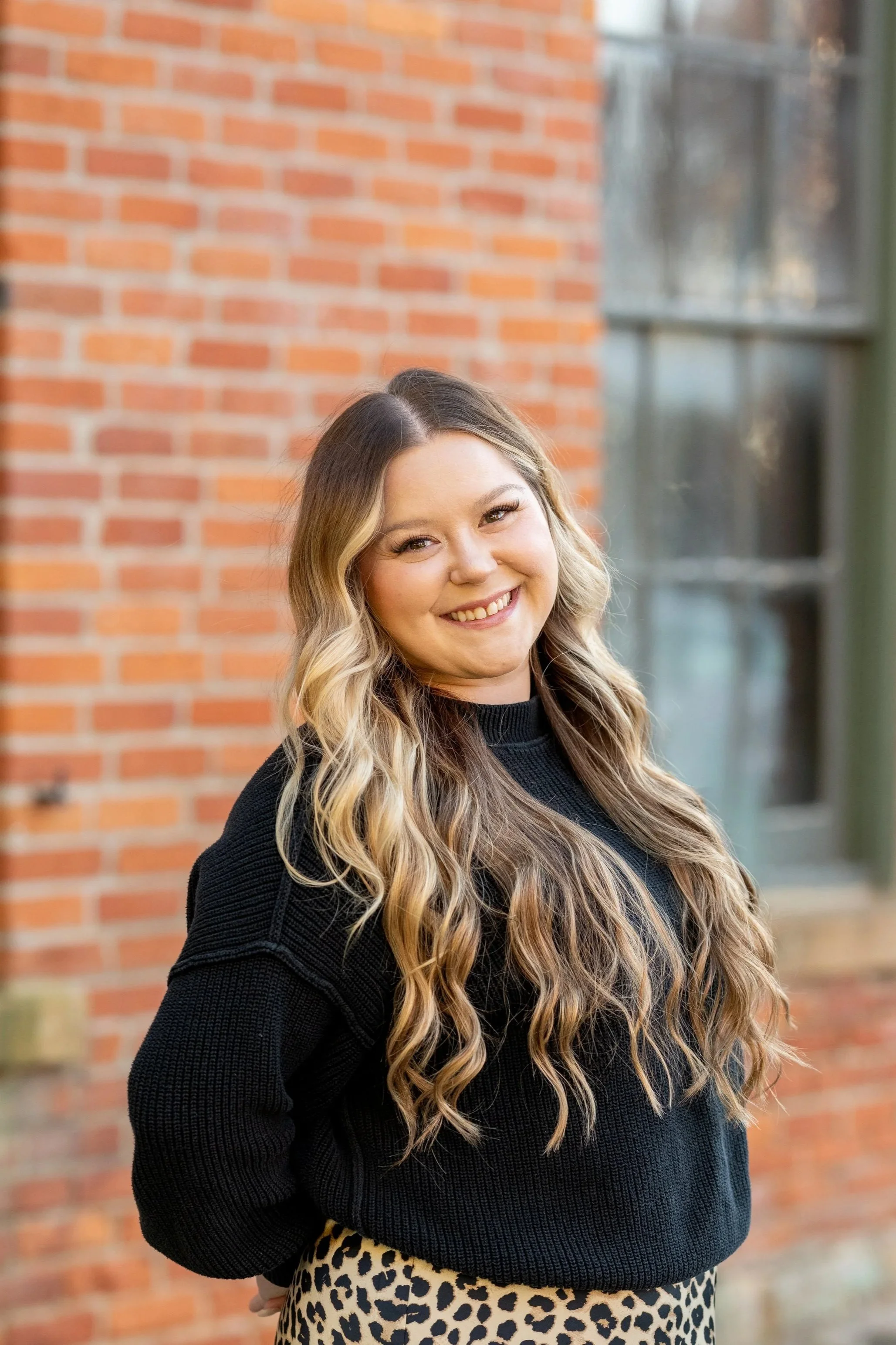 Alex Howard, wearing a black sweater with long blonde hair and a bright smile.