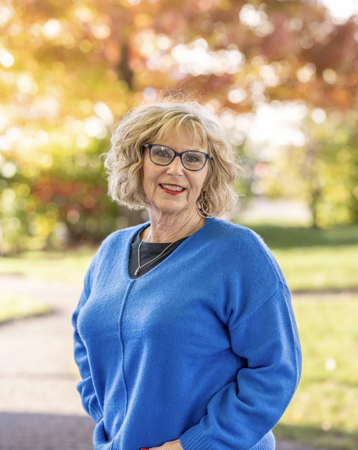 Wendy Ash, with short, blonde hair and glasses. Wearing a blue sweater and a welcoming smile.