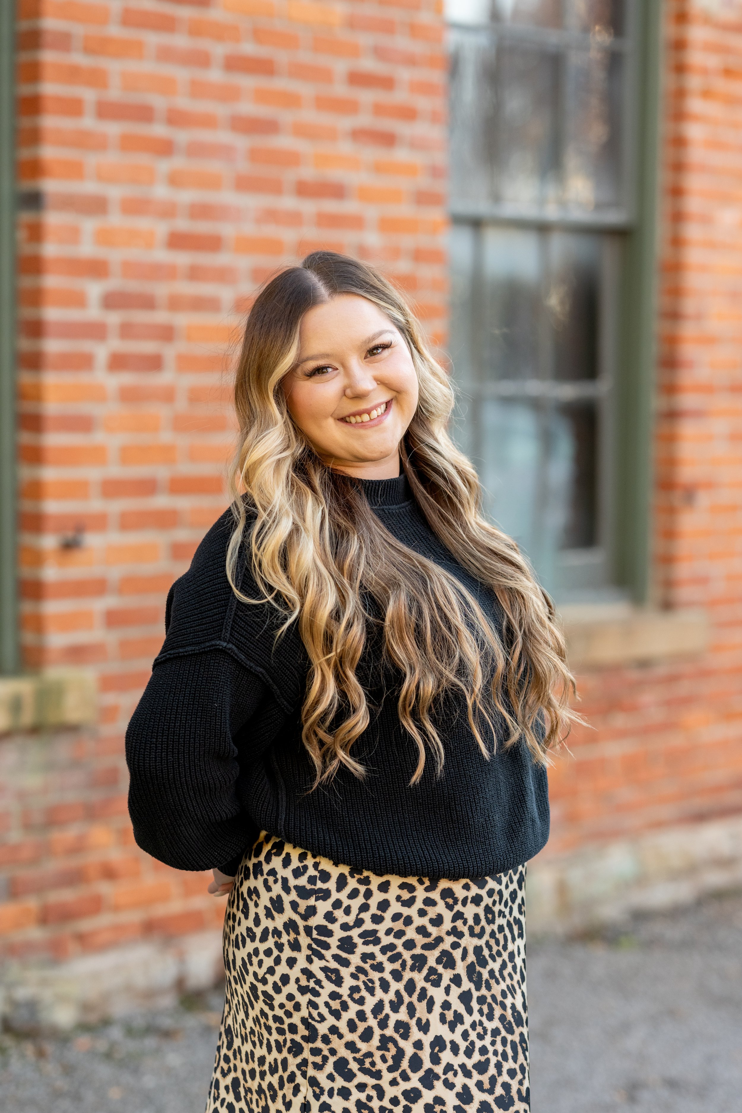 Alex Howard, wearing a black sweater with long blonde hair and a bright smile.