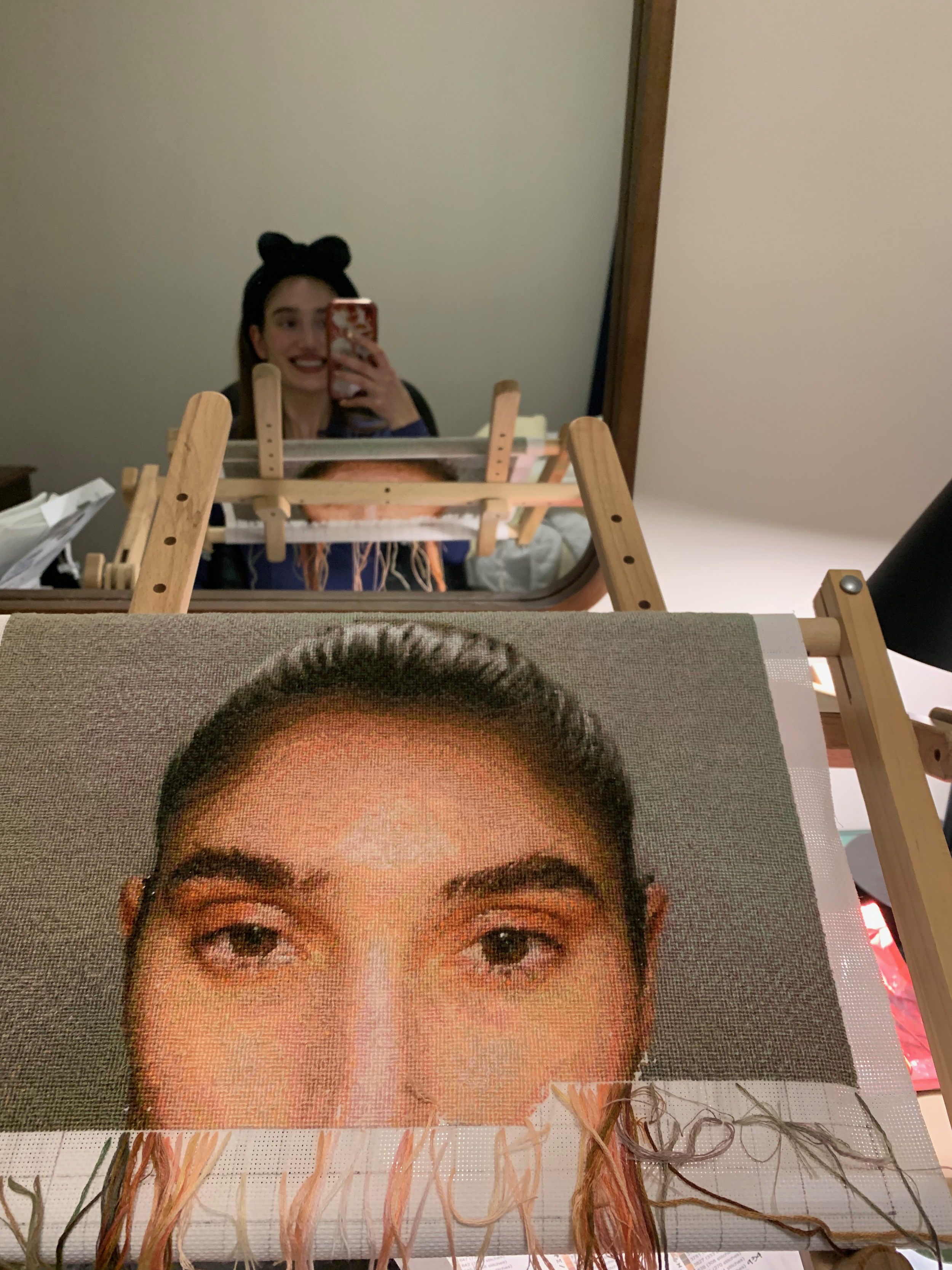 artist posing with hand-stitched portrait on adjustable wooden needlepoint embroidery tapestry scroll frame