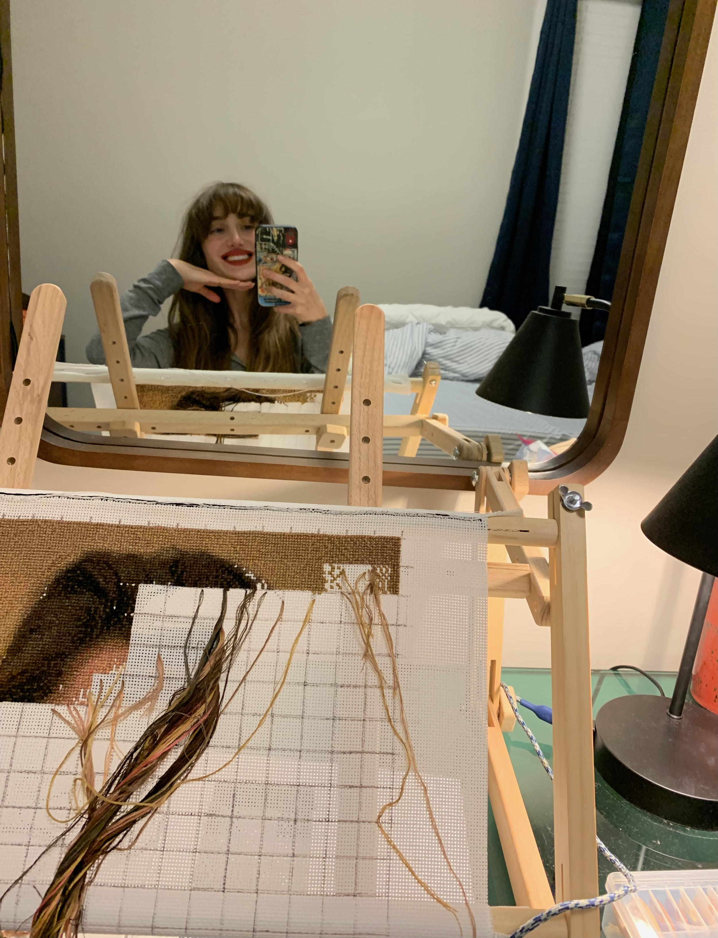 artist posing with hand-stitched portrait on adjustable wooden stand for embroidery