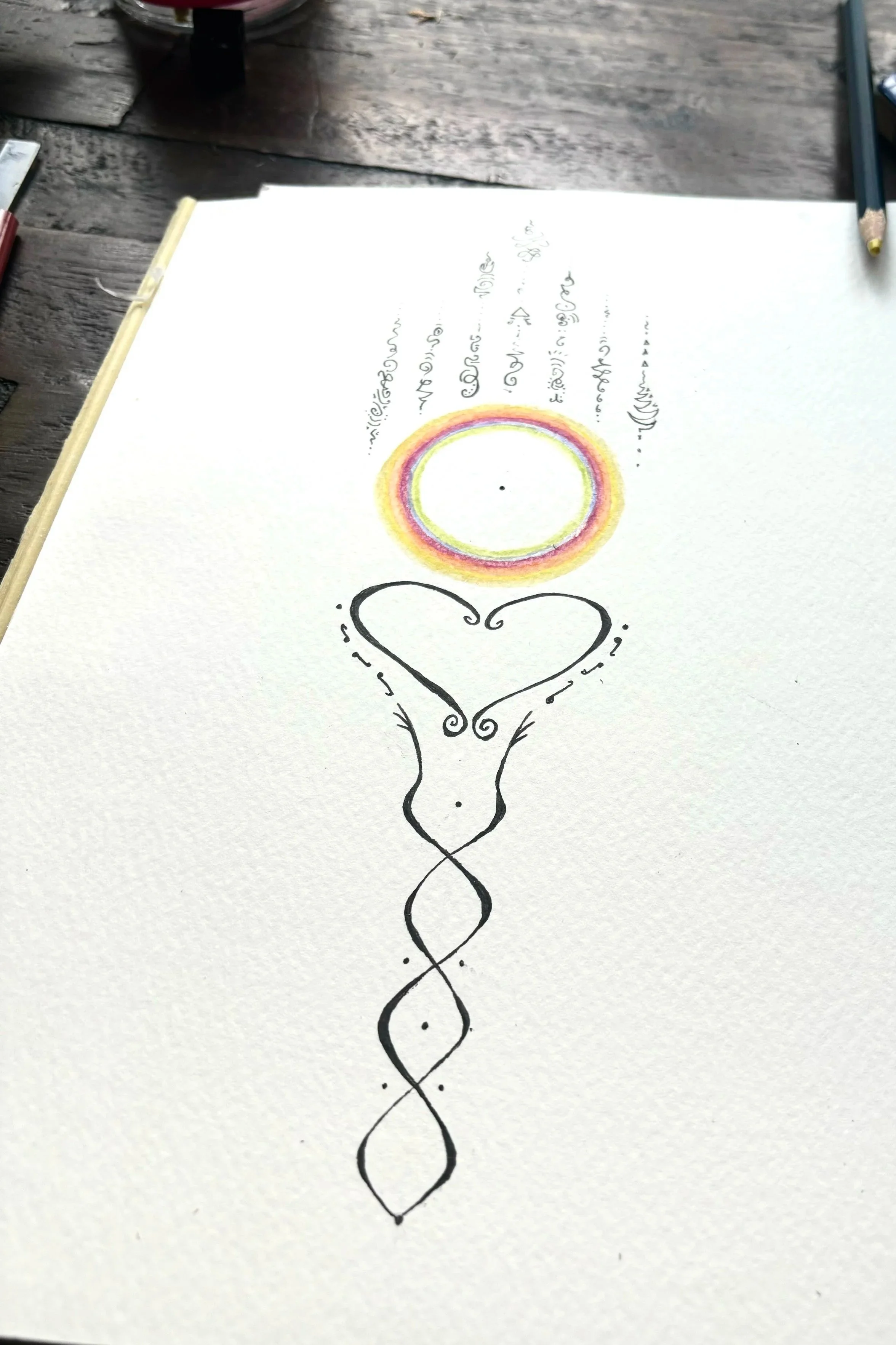 Julie Pack's hand-drawn heart with a stylized, elongated, spiral-like design extending downward, with rainbow-colored concentric rings and handwritten text above it on white paper.