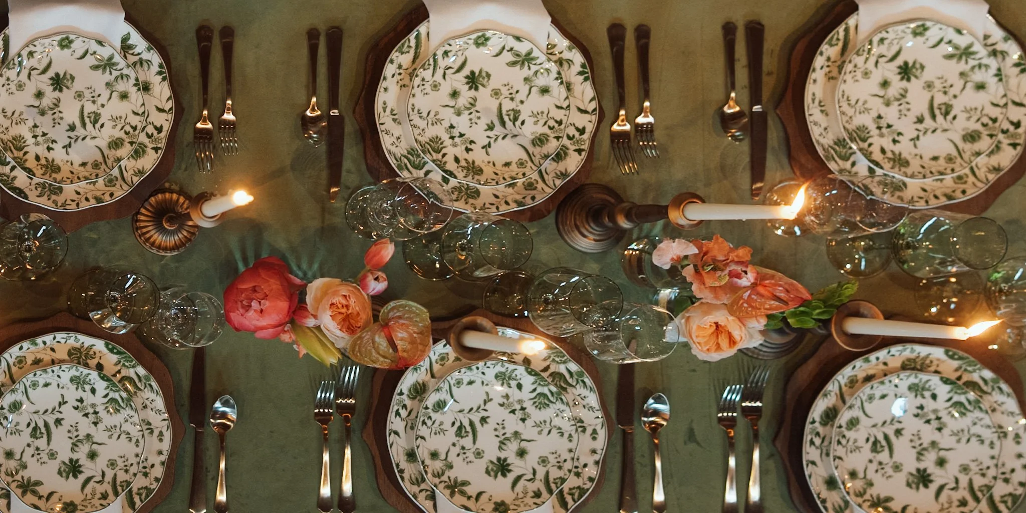 A top-down view of a formal dining table set with plates, silverware, candles, and floral decorations.