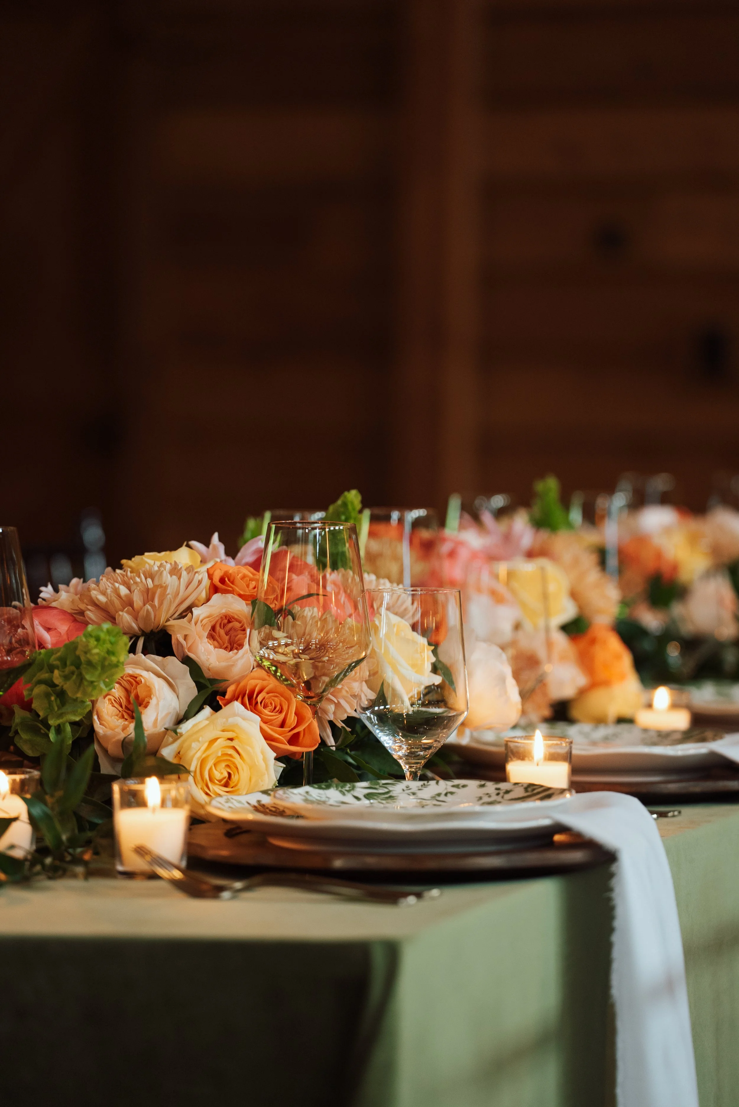 A beautifully decorated table with a large floral centerpiece, glassware, candles, and elegant table settings for a celebration or special event.