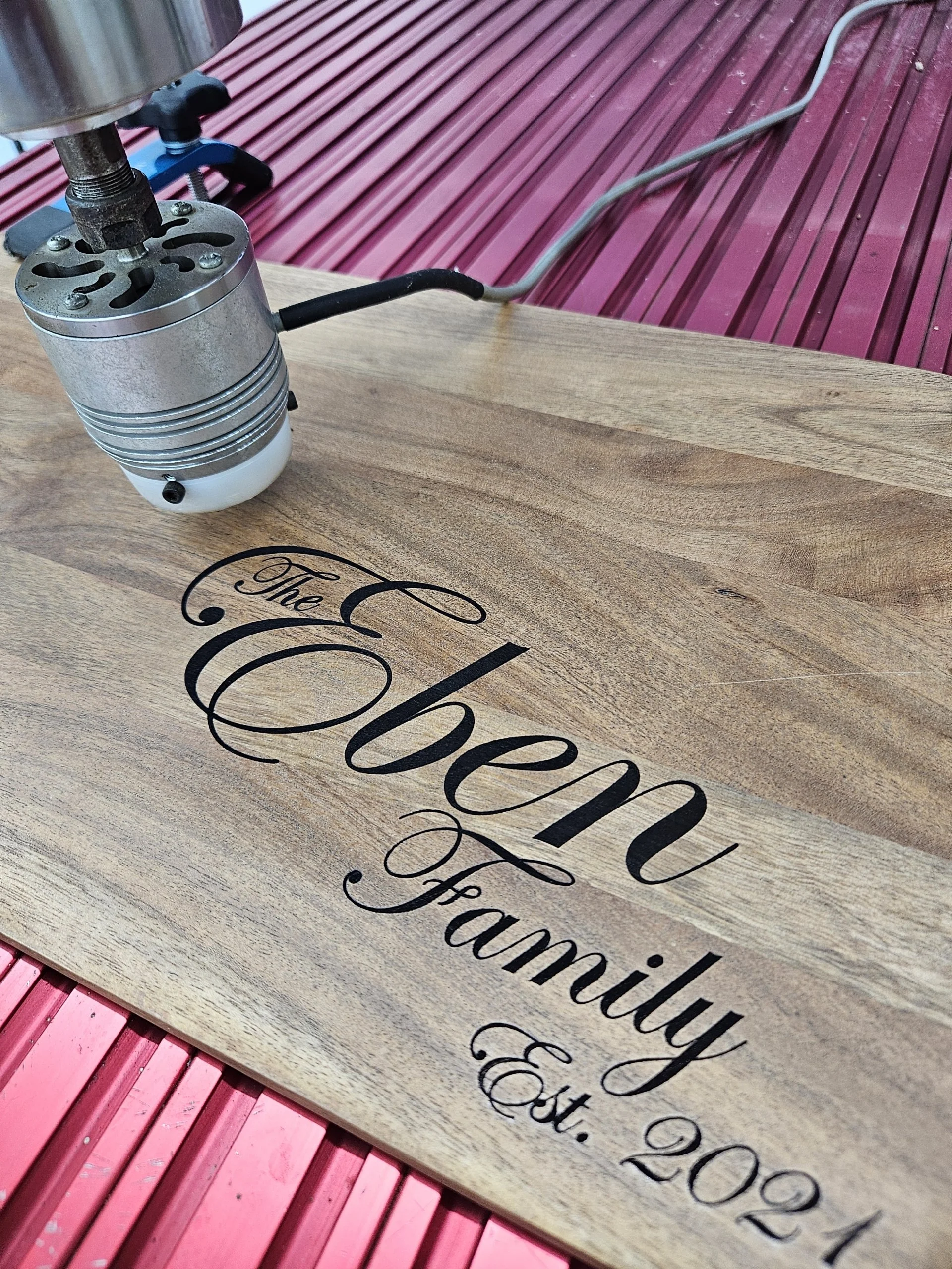 Close-up of a small engine or motor placed on a wooden surface with printed text, with a pink slatted background.