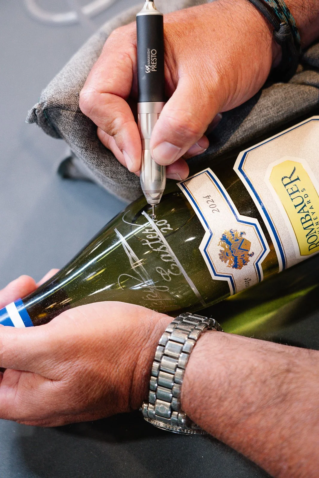 Grady hand engraving champagne bottle in retail booth engraving set up