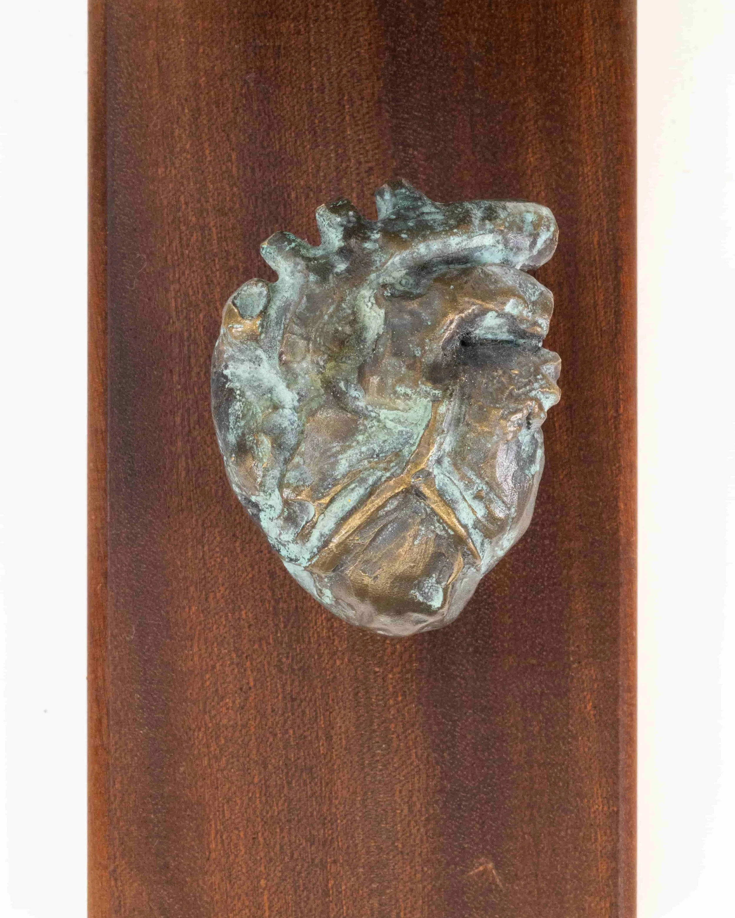 Close-up of a metallic, textured, heart-shaped object resting on a wooden surface.