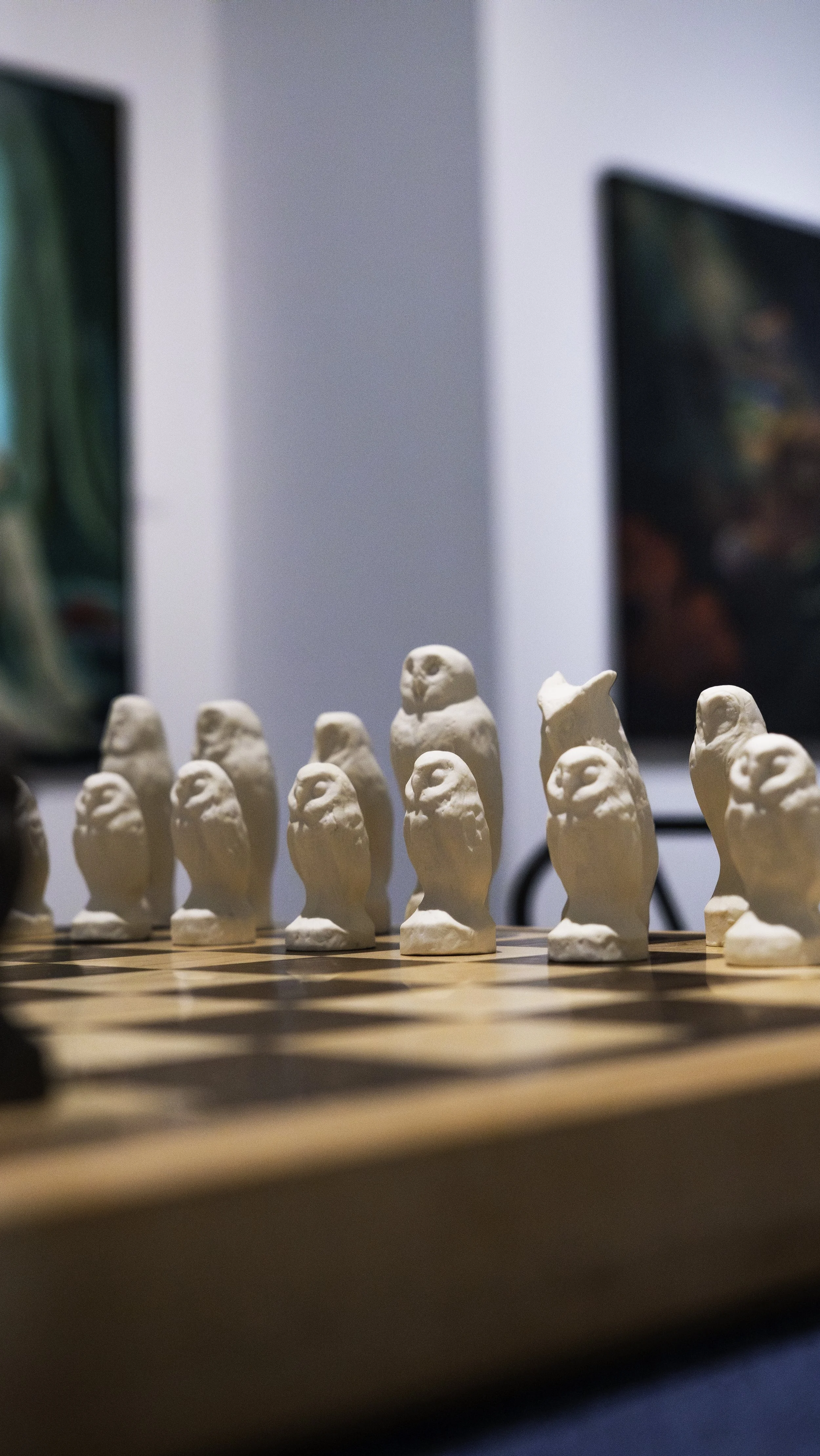 A chessboard with white chess pieces arranged in the starting position, with blurred colorful artwork in the background.