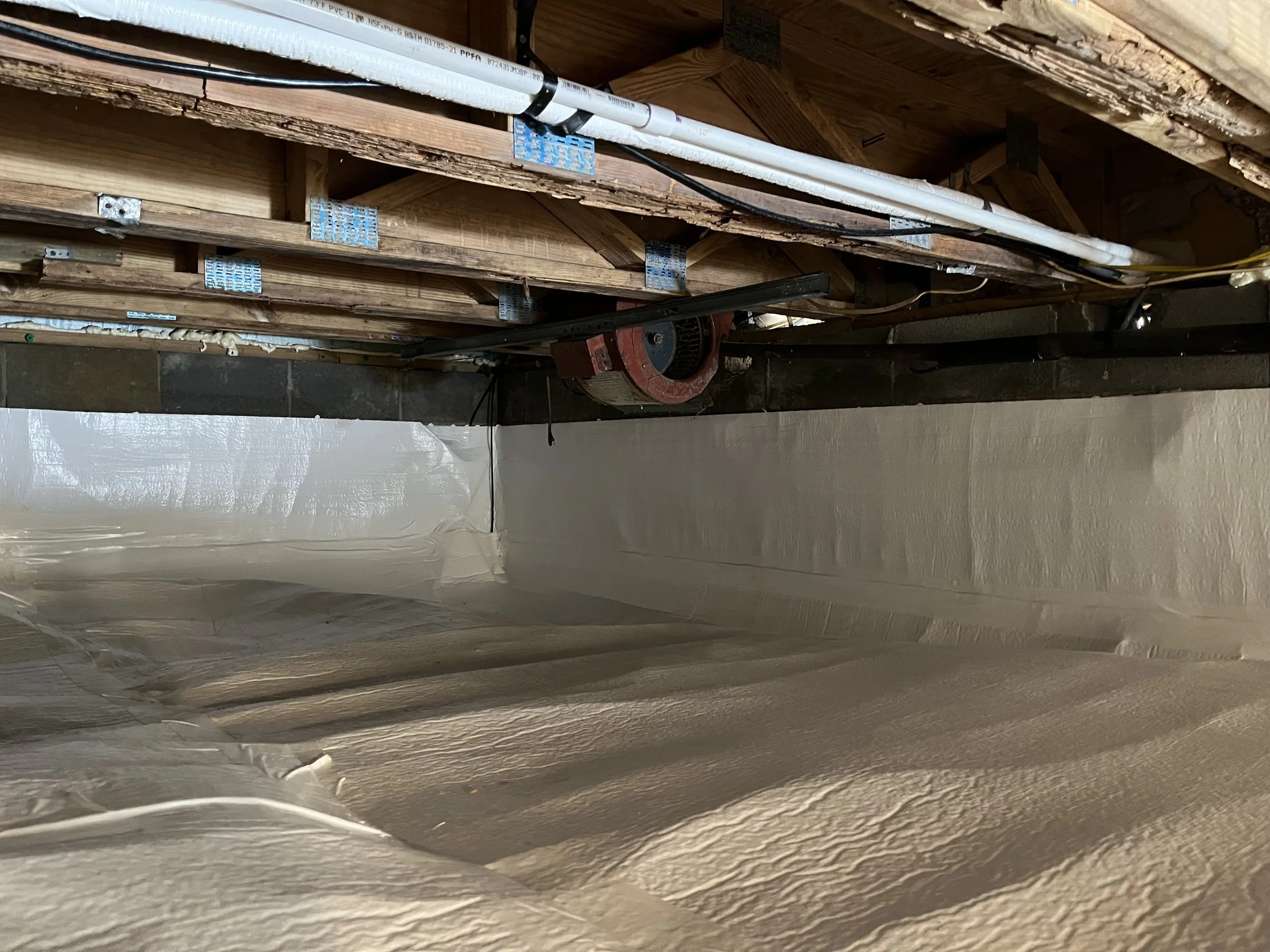 View of unfinished attic space with exposed wooden beams, insulation, and electrical wiring.