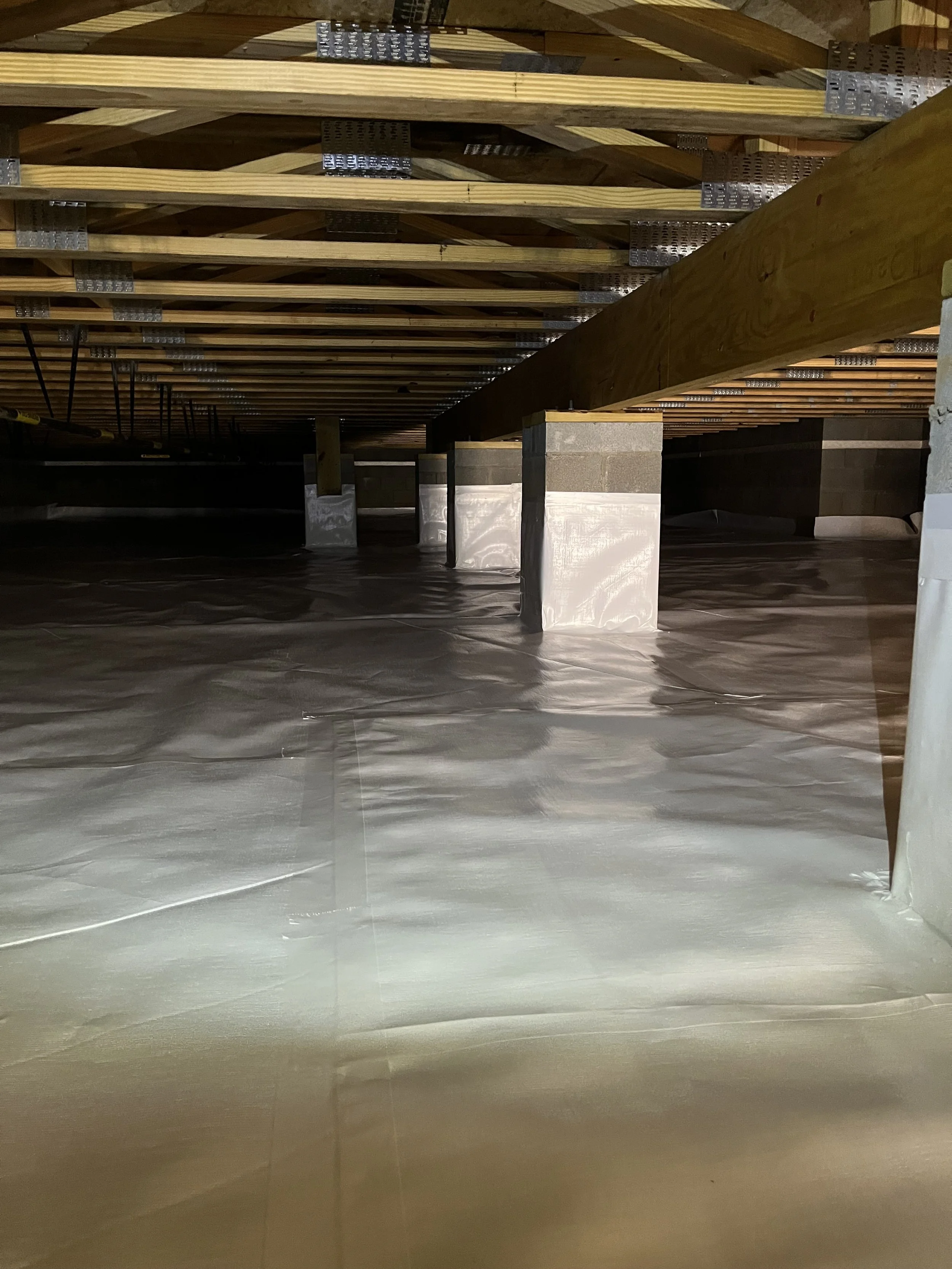 Under construction or renovation site with wooden beams and supports, covered with protective plastic on the floor.
