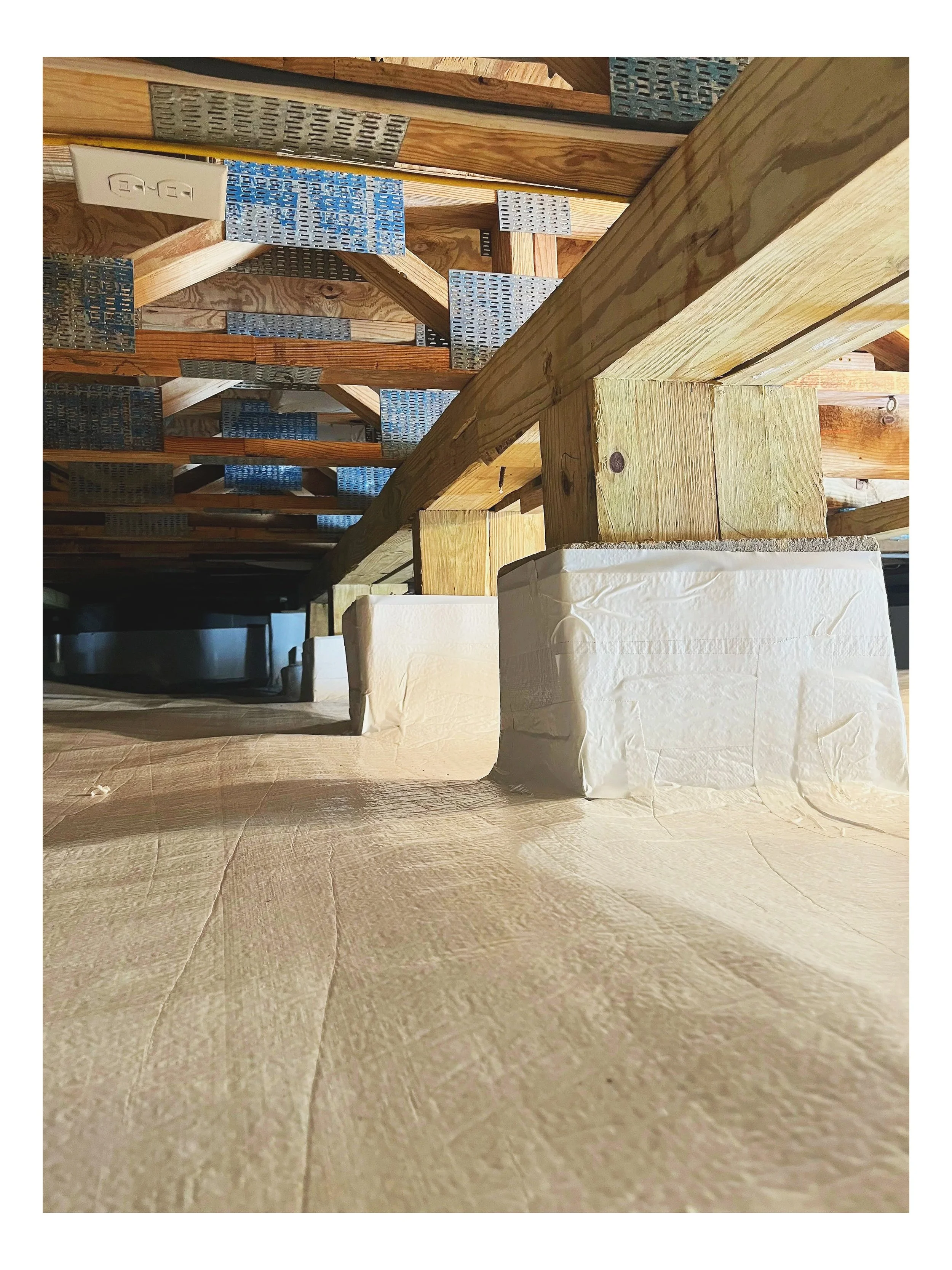 View of a wooden loft with metal brackets and supports, showing a partially finished construction space with beige tiled flooring.