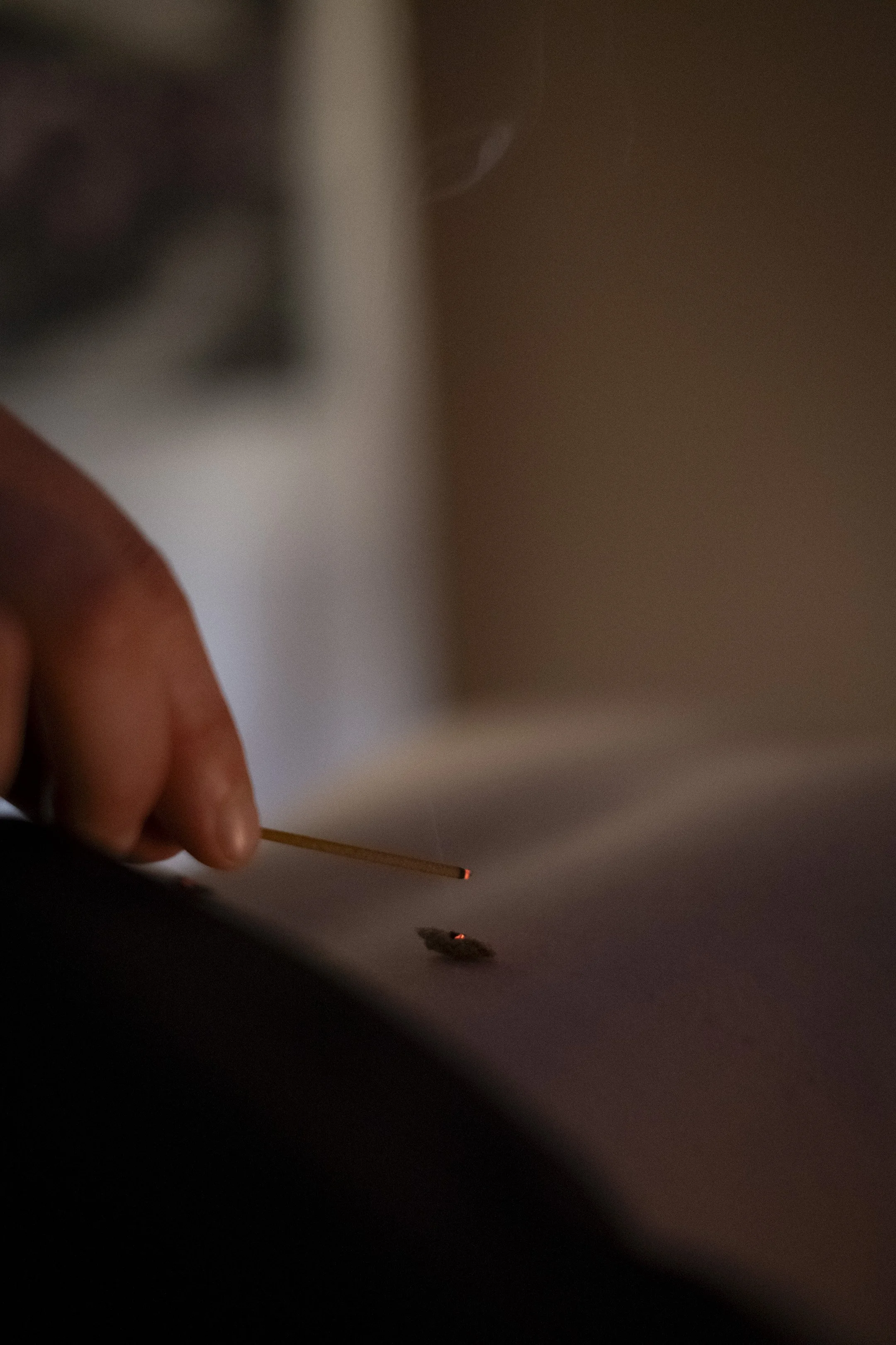 A practitioner gently lights a cone of moxa with an incense stick, preparing a traditional moxibustion treatment that uses warmth to support balance and wellbeing.