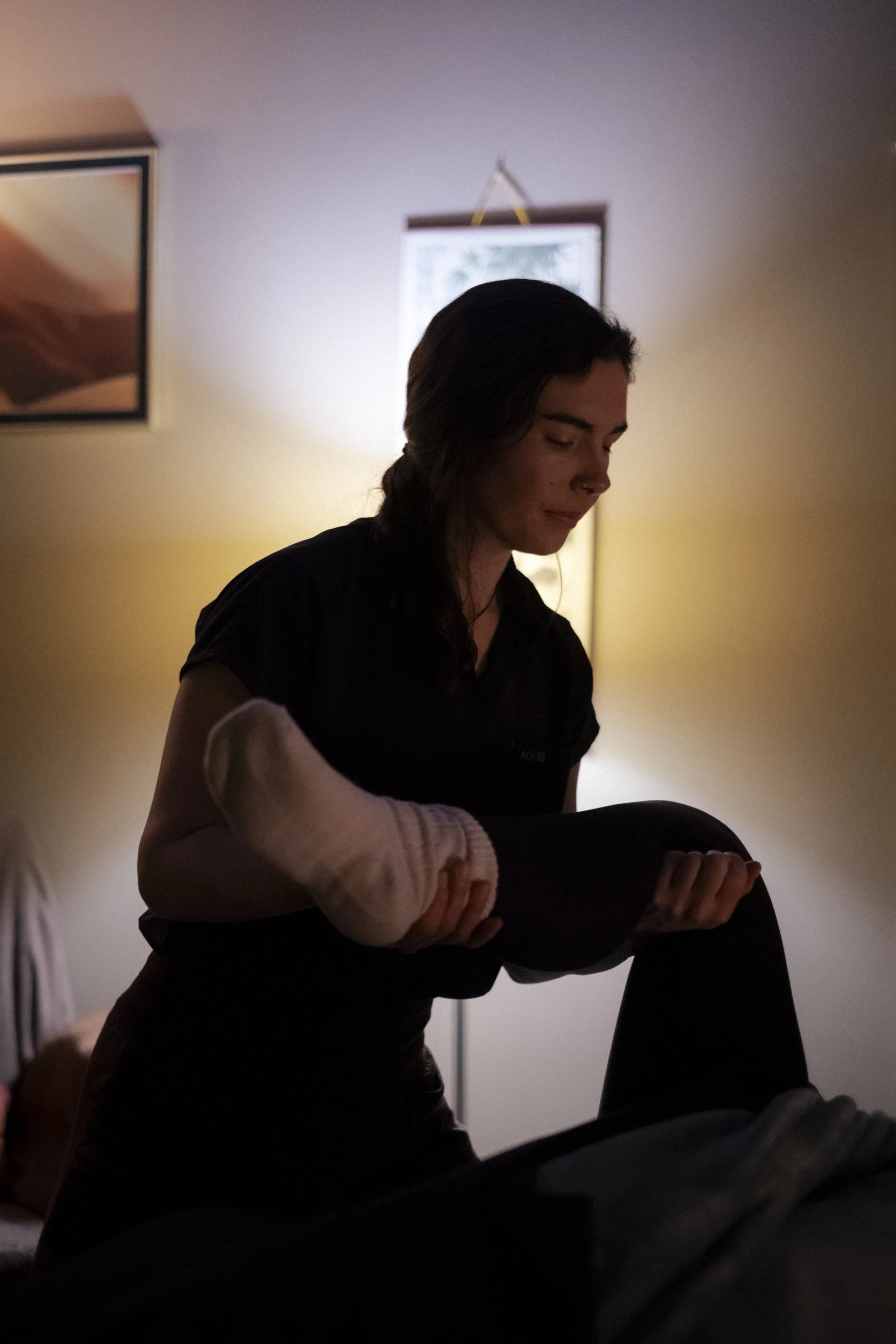 A massage therapist guides a client’s leg through passive range of motion during a treatment session.