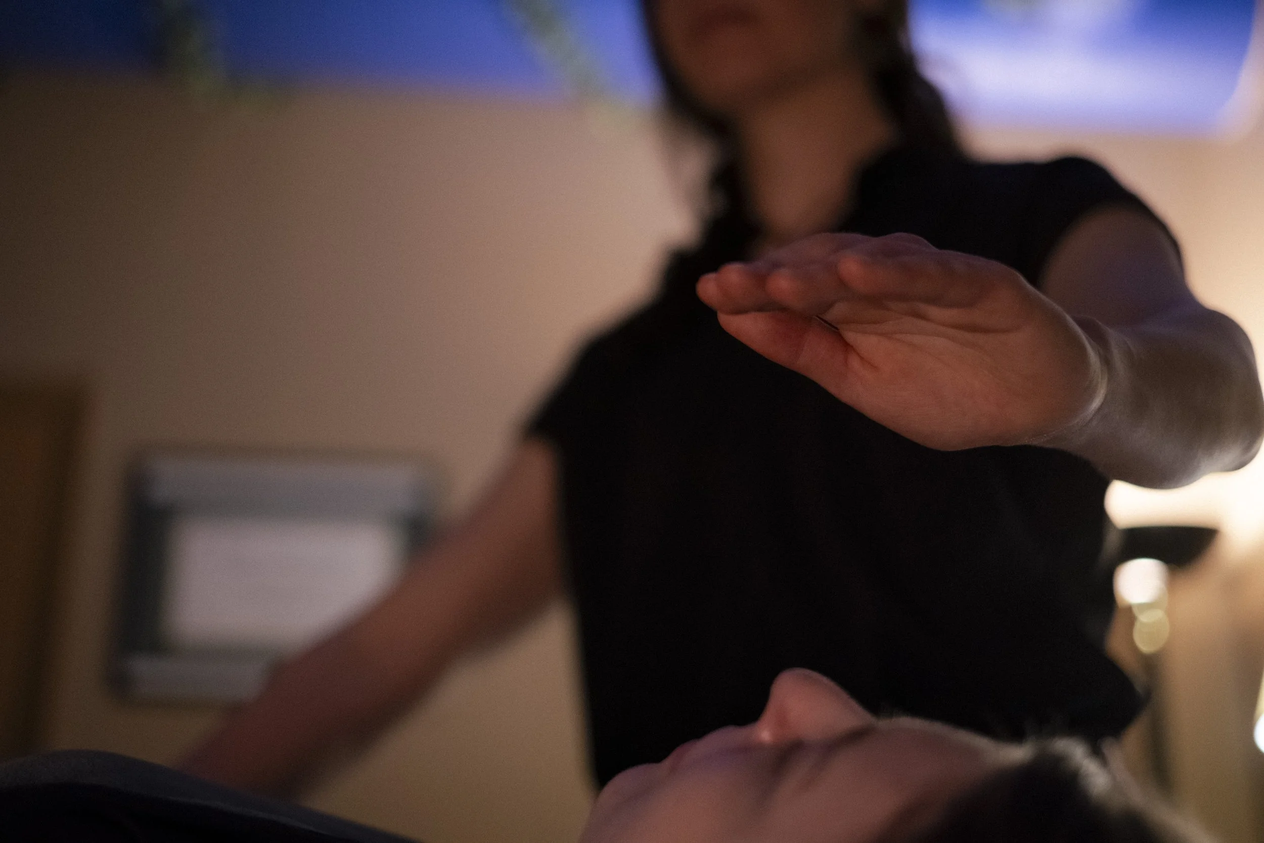 A practitioner offers energy work at the third eye, supporting relaxation and inner balance during a treatment session.