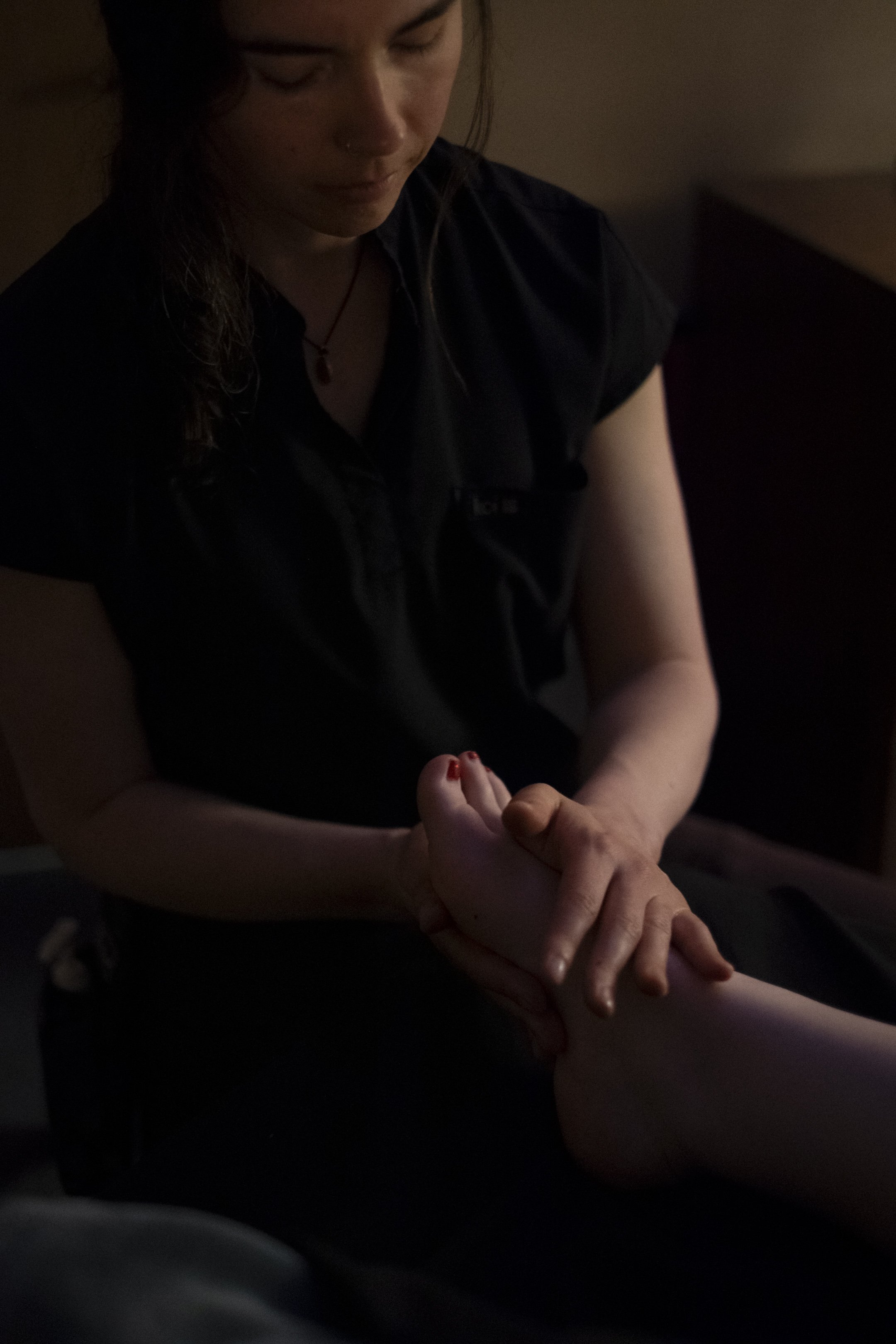 A massage therapist provides a foot massage to a client during a treatment session.