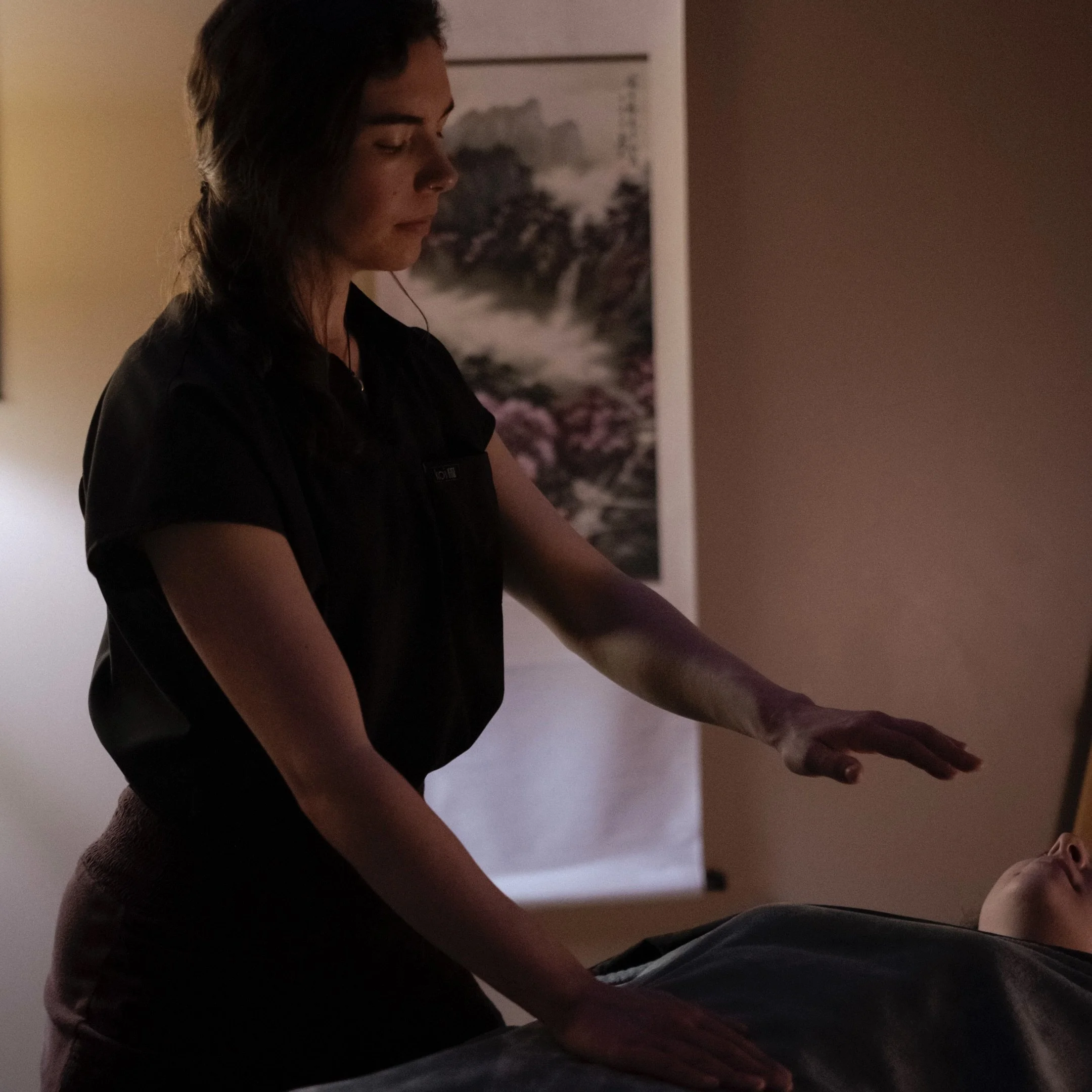 A practitioner offers energy work during a client session, supporting balance and relaxation.