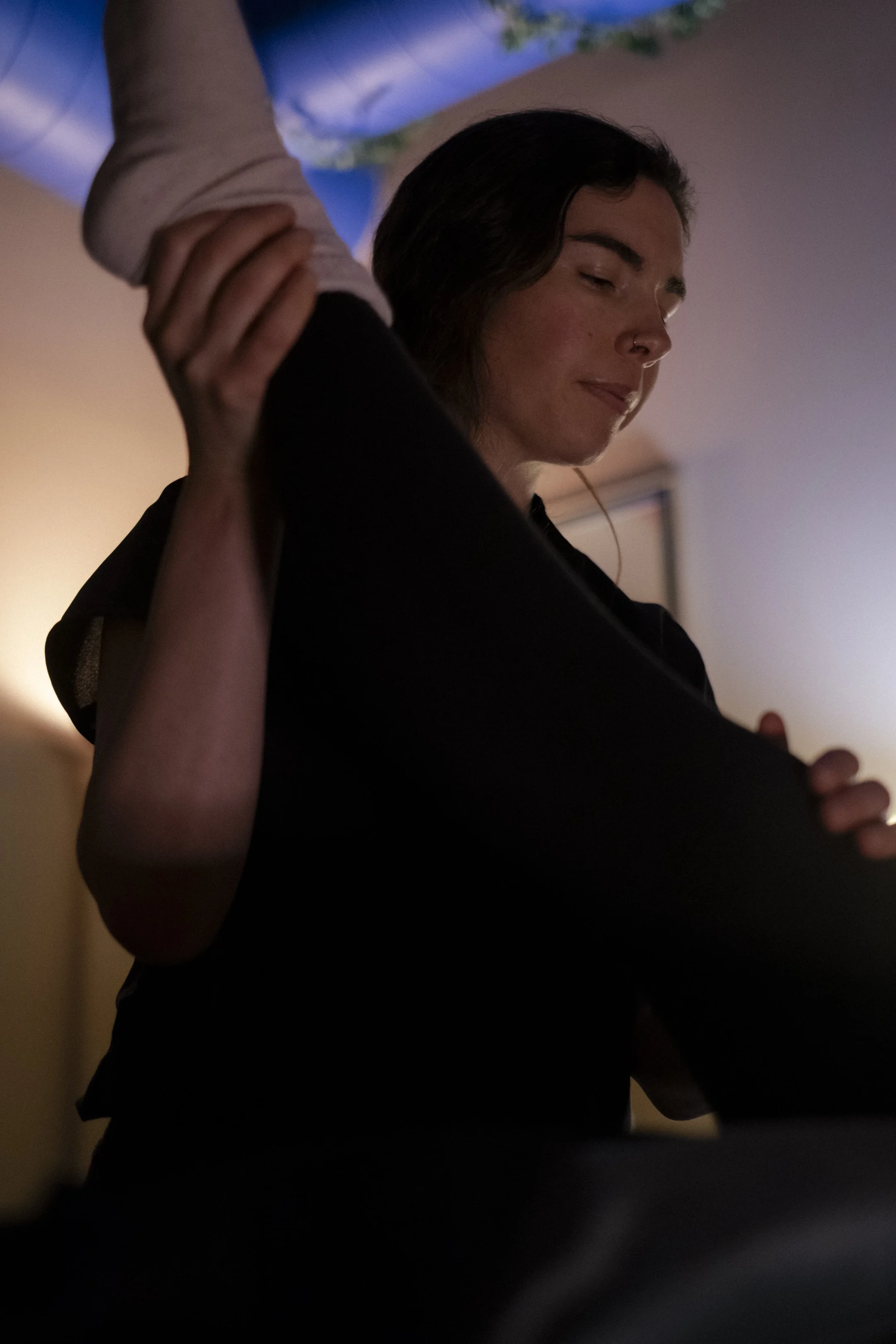 A massage therapist guides a client’s leg through passive range of motion during a treatment session.