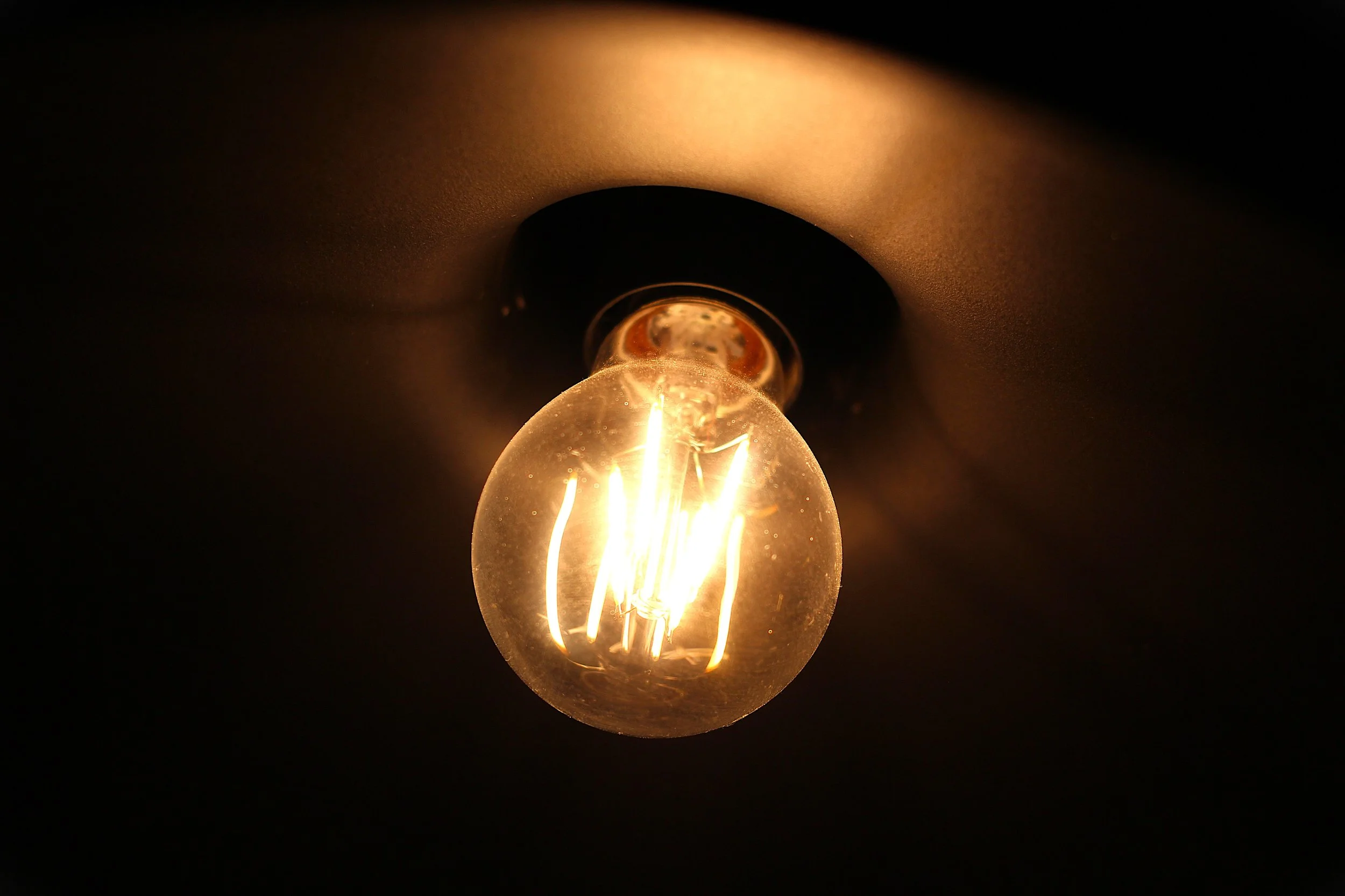 En glödlampe avtänt i mörker, med synligt glödande filament.