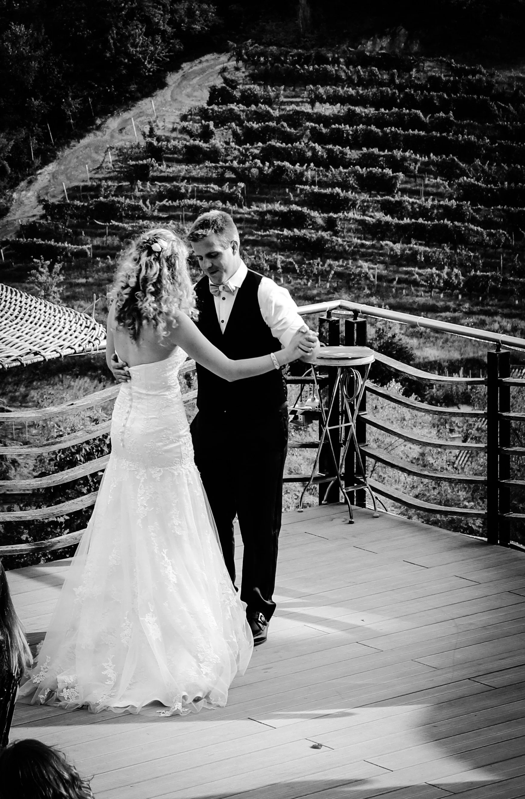 En brud och en brudgumma dansar på en trätrappa med landskap i bakgrunden.