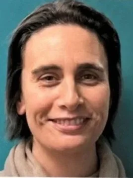 Close-up of a woman with dark hair, smiling, against a teal background.