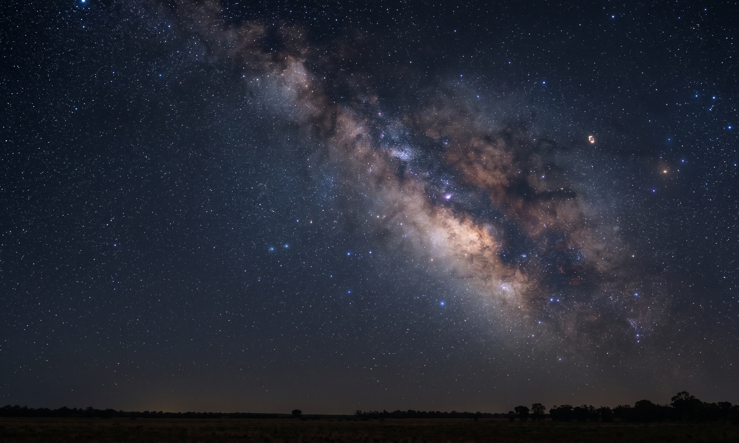 A night sky filled with stars and the Milky Way galaxy, with a dark landscape silhouette at the horizon.